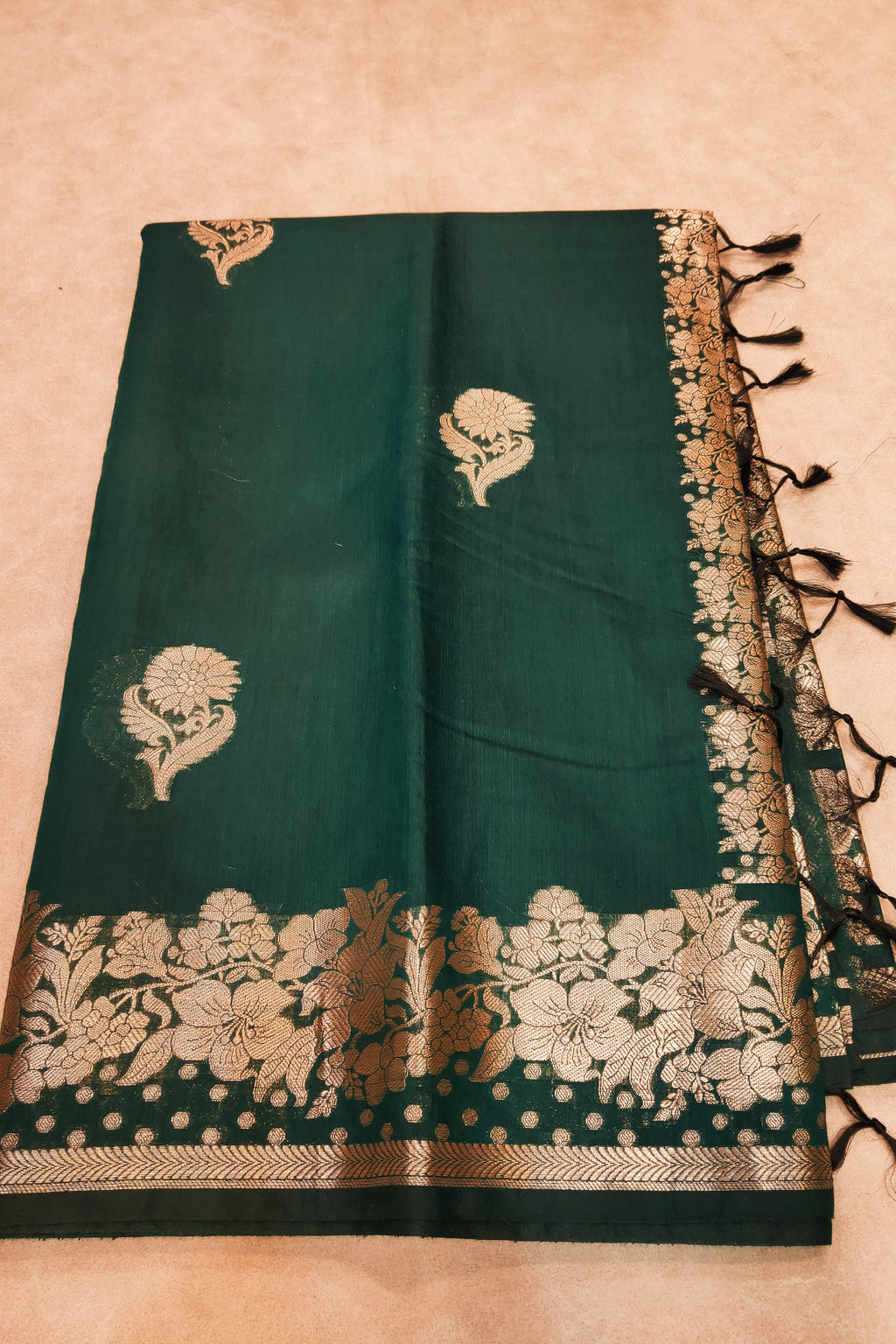 Green saree with gold floral patterns on a beige background