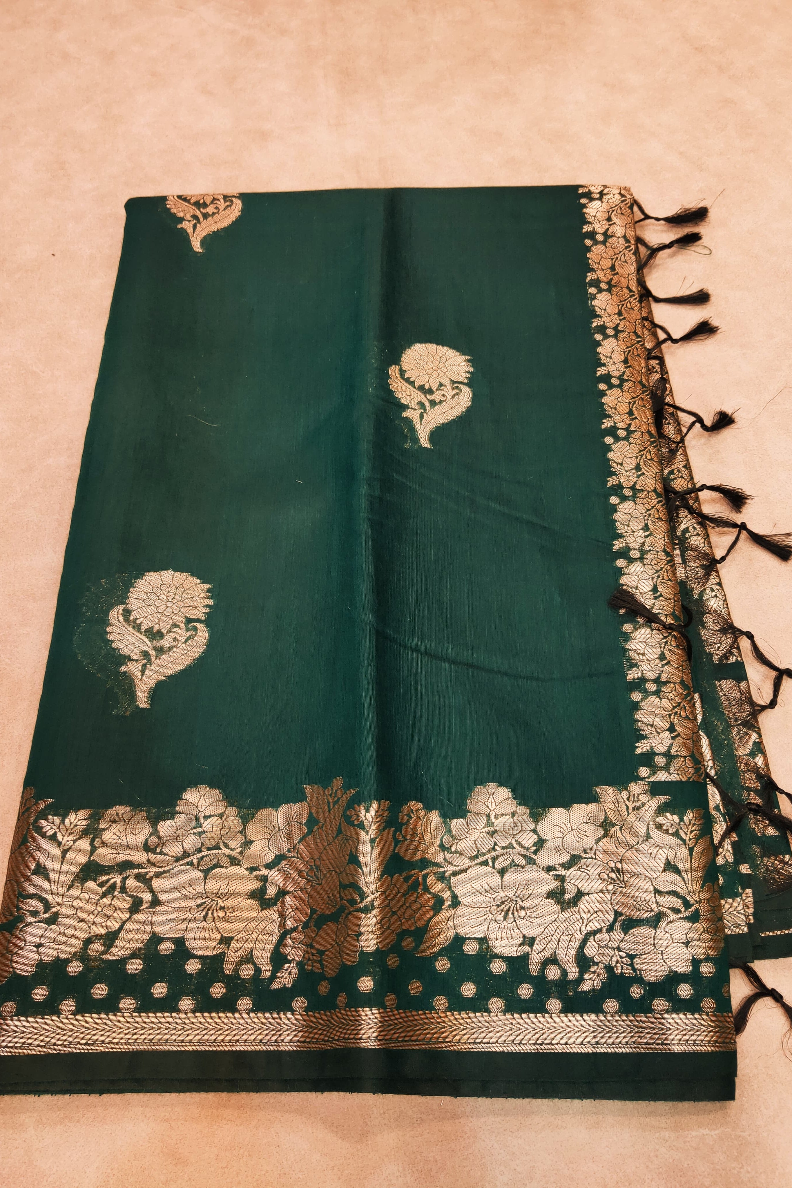 Green saree with gold floral patterns on a beige background
