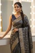 Woman in a saree standing in front of vanity mirrors with lights.