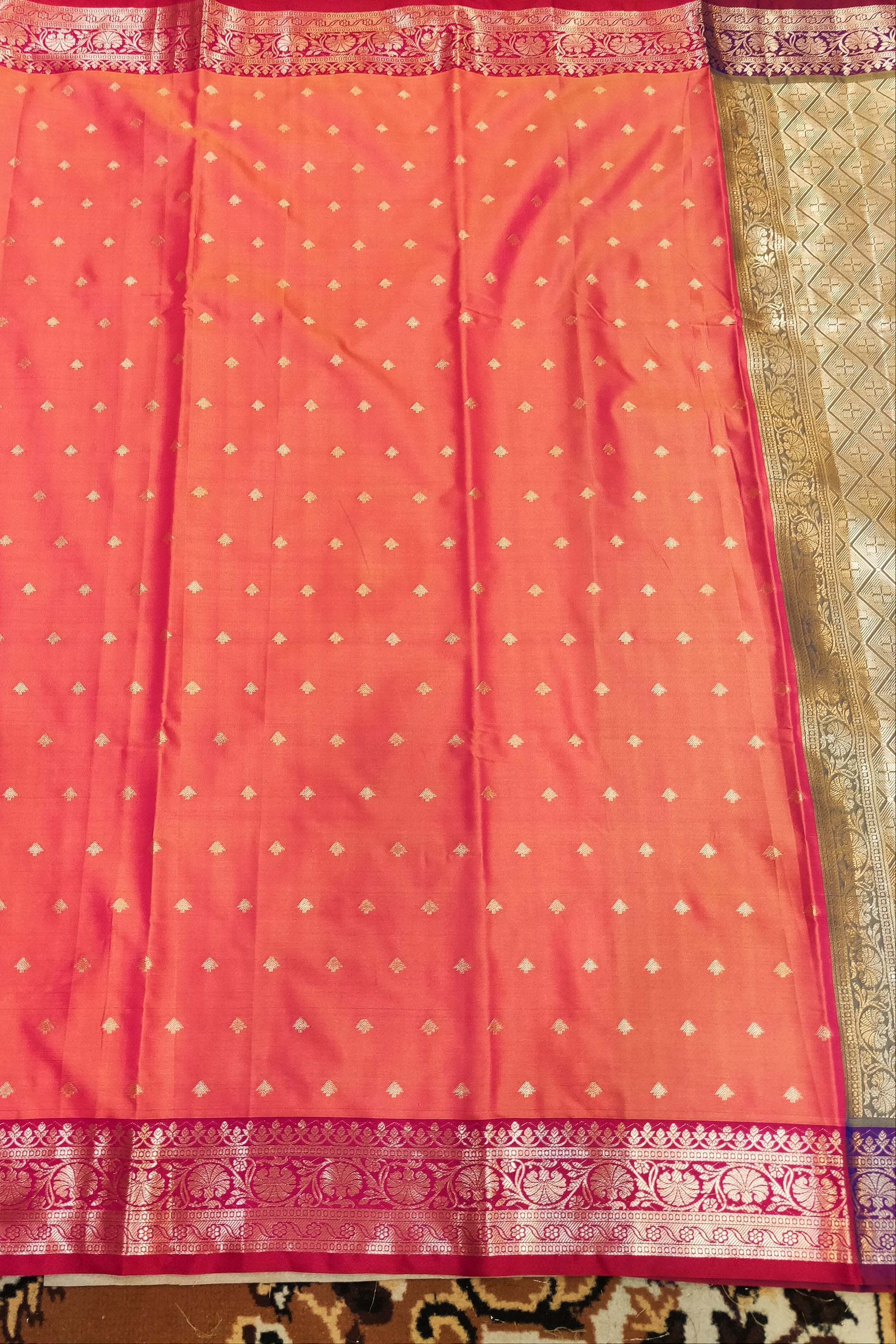 Pink saree with white patterns and a decorative border on a patterned fabric background