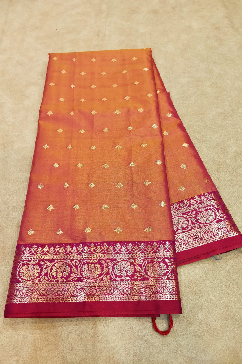 Orange and red saree with intricate patterns on a beige background