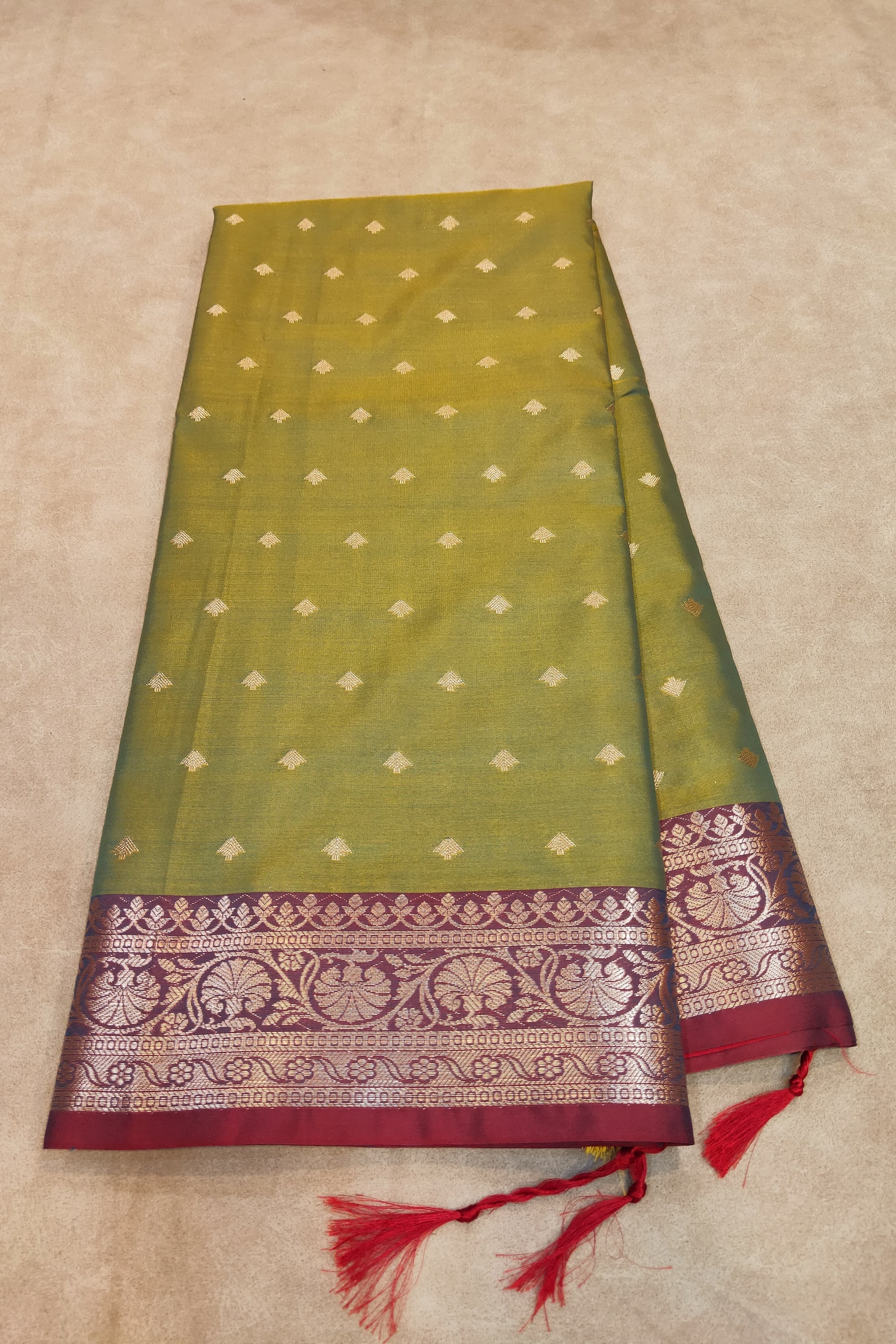 Green saree with a red border on a beige background