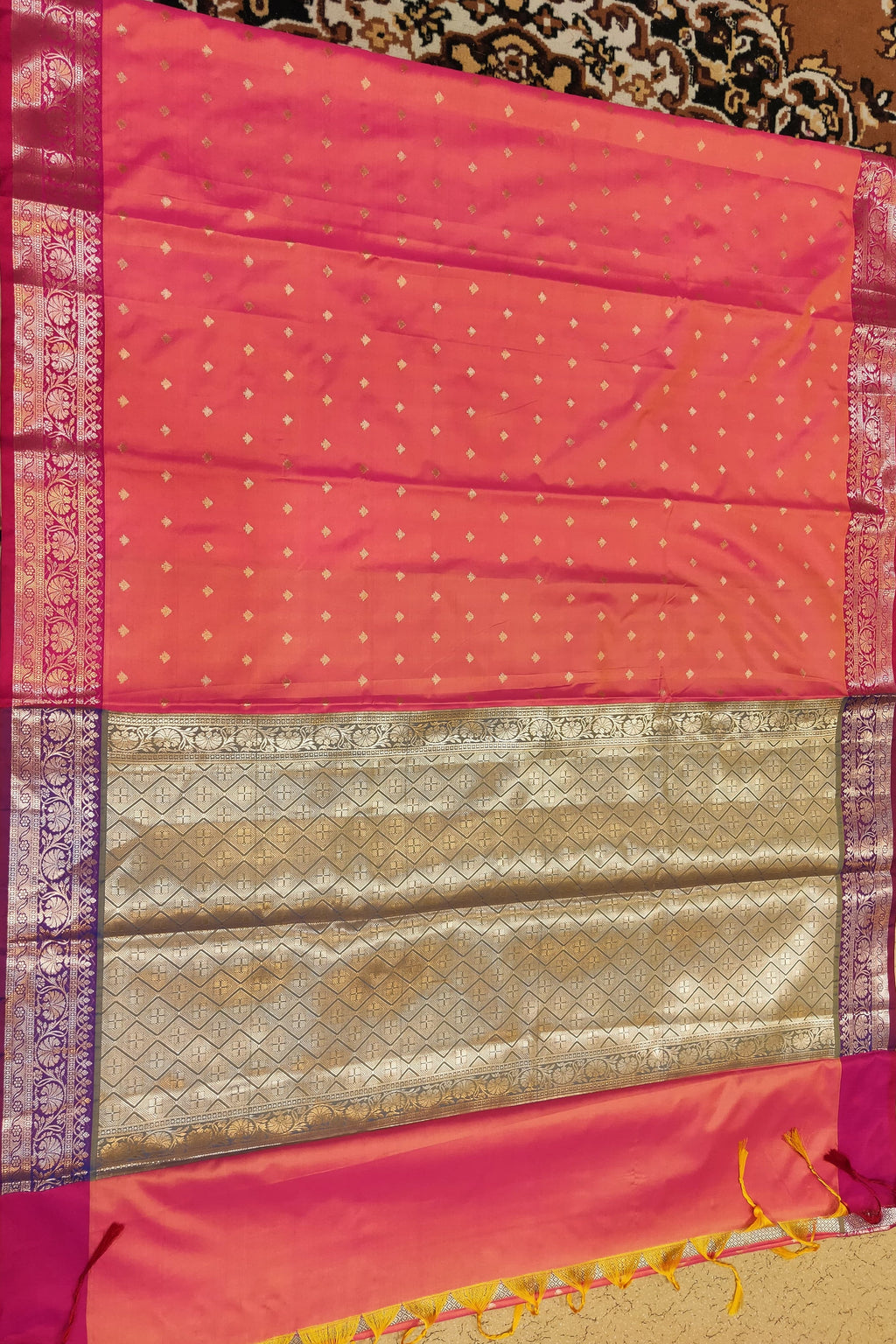 Pink saree with a patterned border on a textured surface