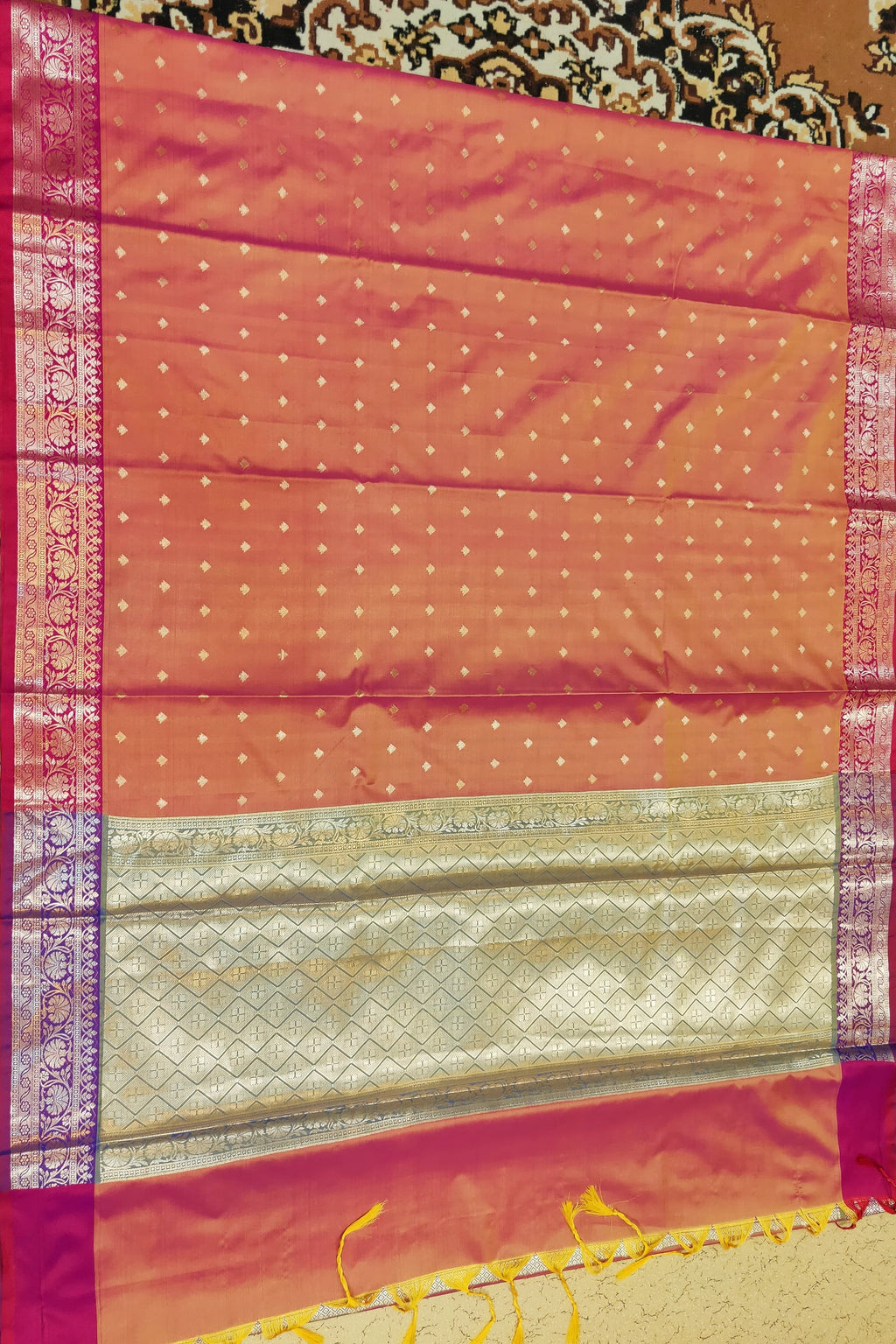 Traditional saree with a pink border and gold pattern on a textured background