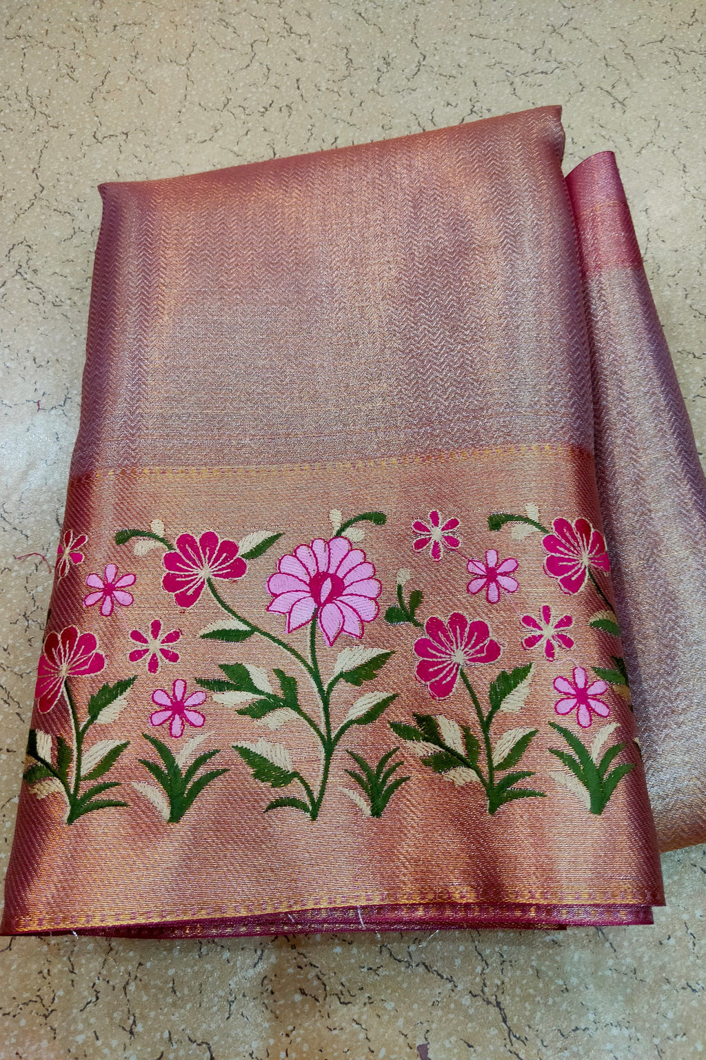 Embroidered fabric with pink flowers on a textured surface