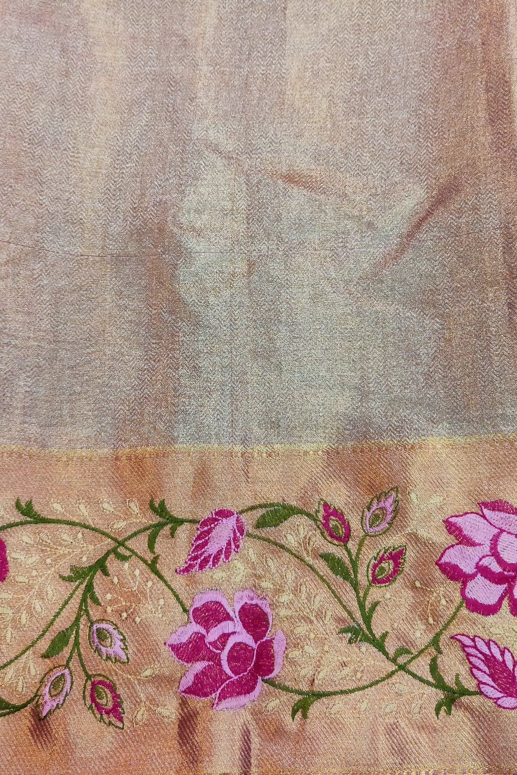 Fabric with floral embroidery held by a hand on a textured surface
