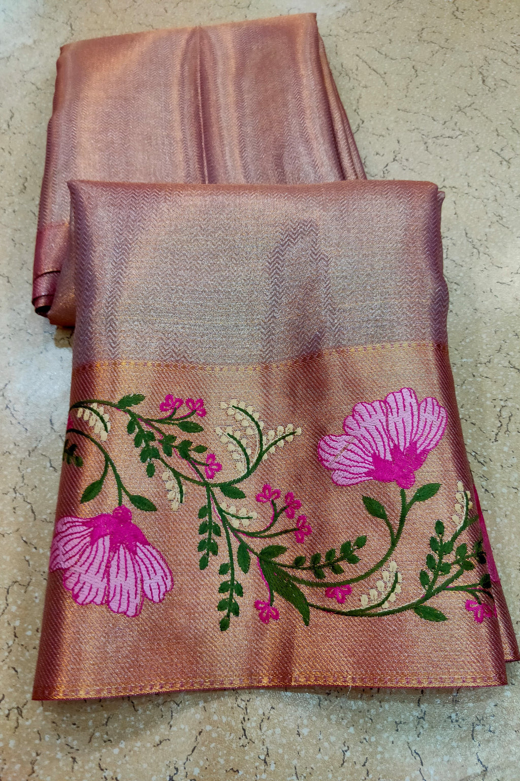 Brown fabric with floral embroidery on a textured surface