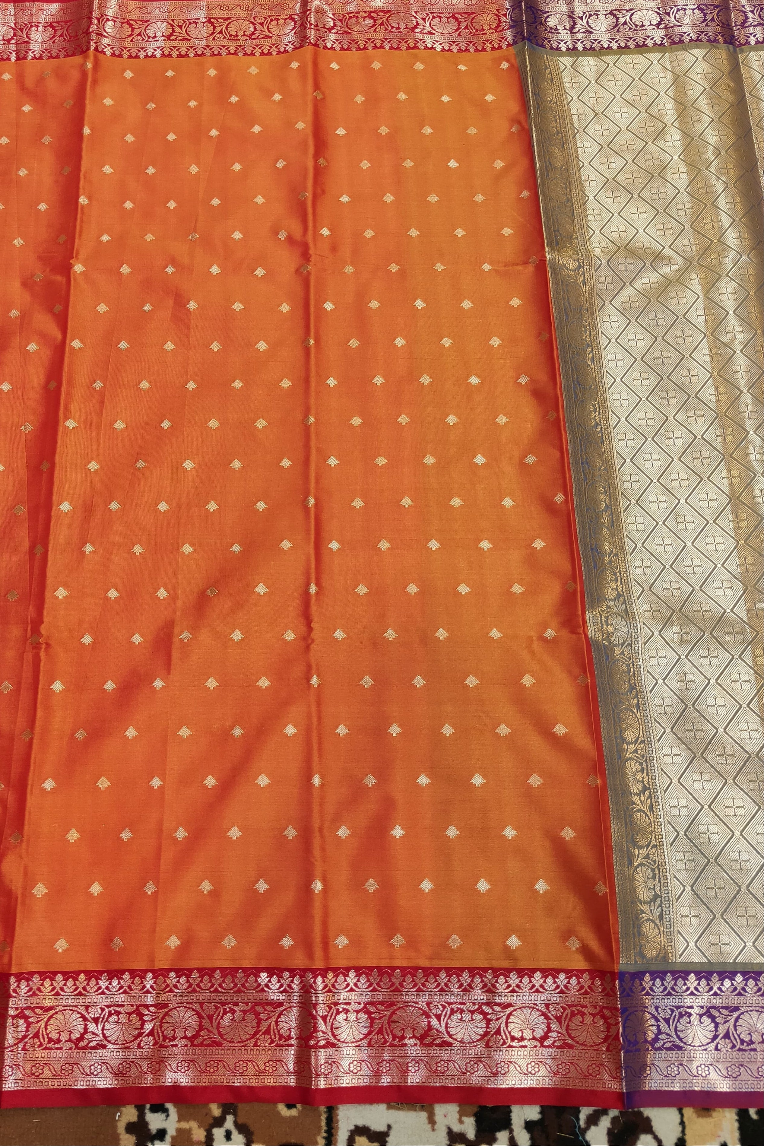 Orange saree with a patterned border on a textured fabric background