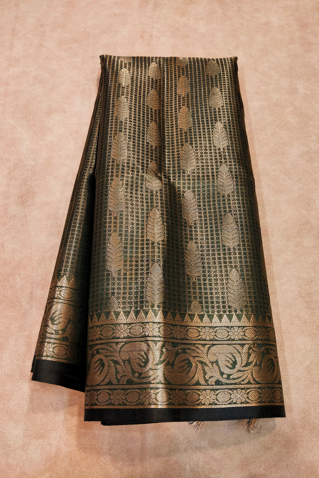Black saree with gold patterns on a beige background