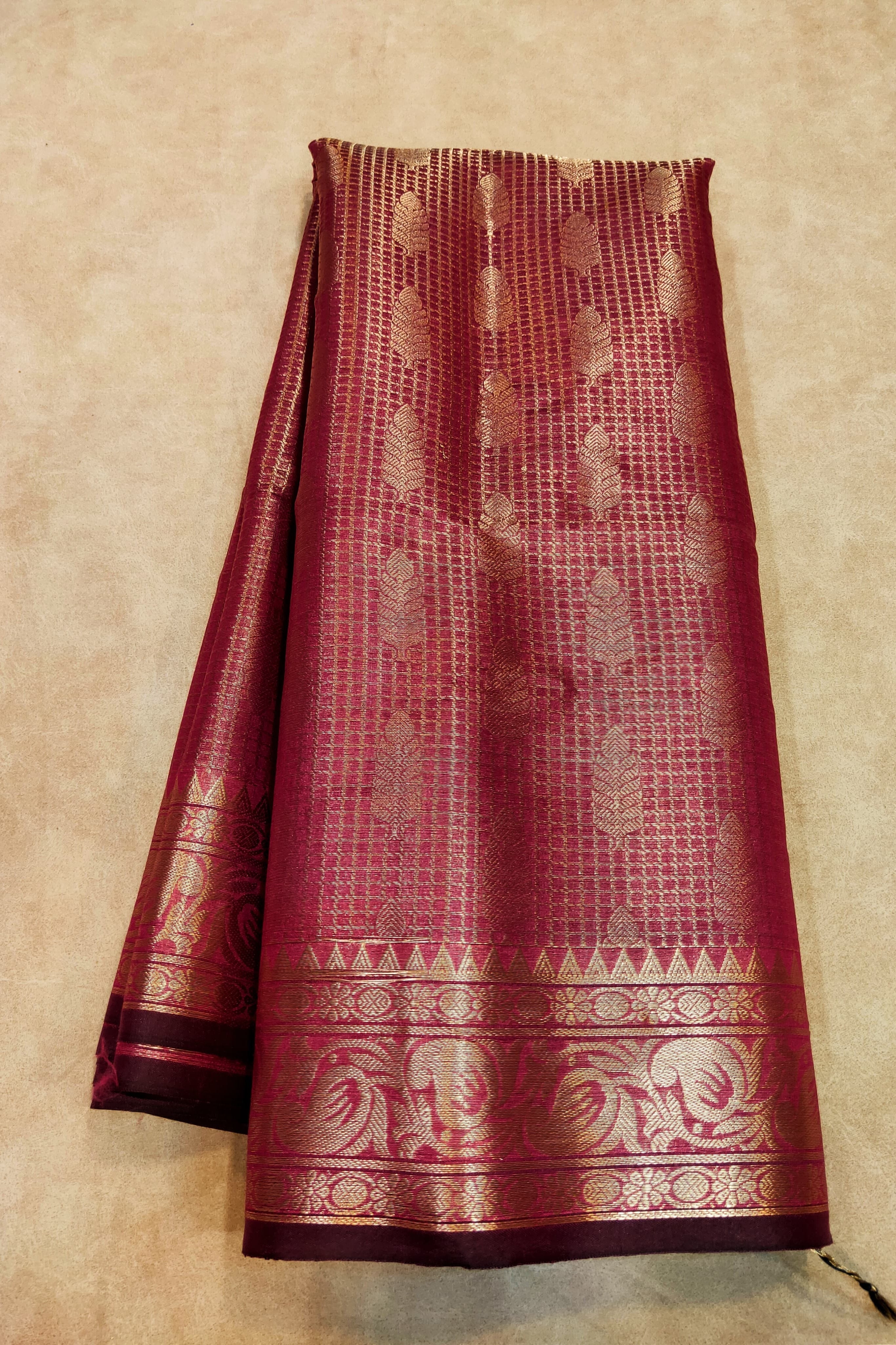 Maroon saree with gold patterns on a beige background