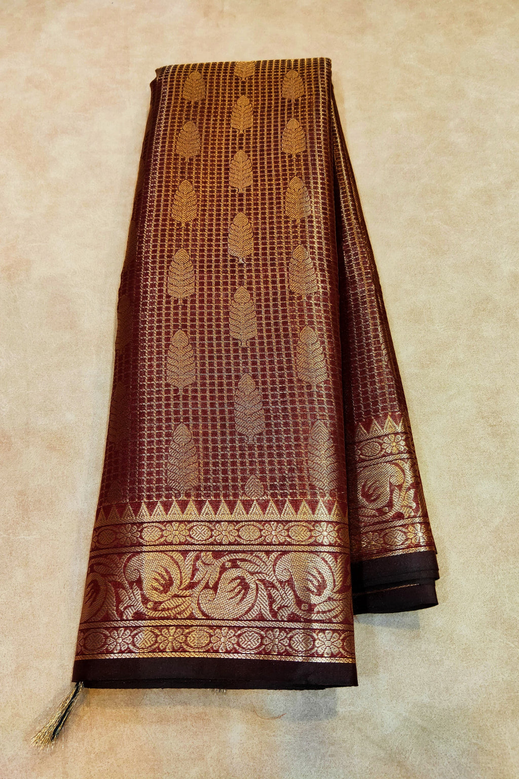 Brown saree with gold patterns on a beige background