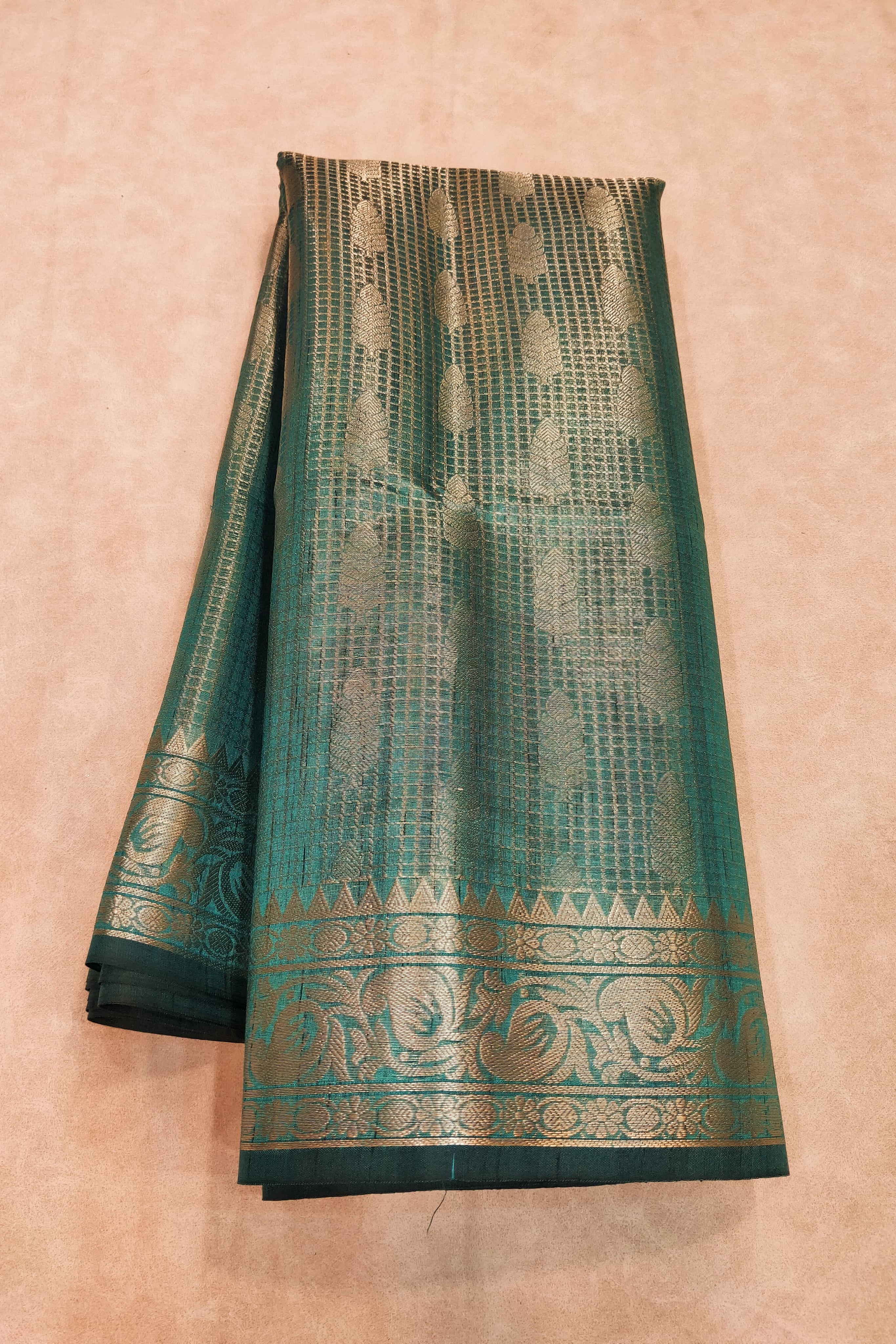 Green saree with gold patterns on a beige background