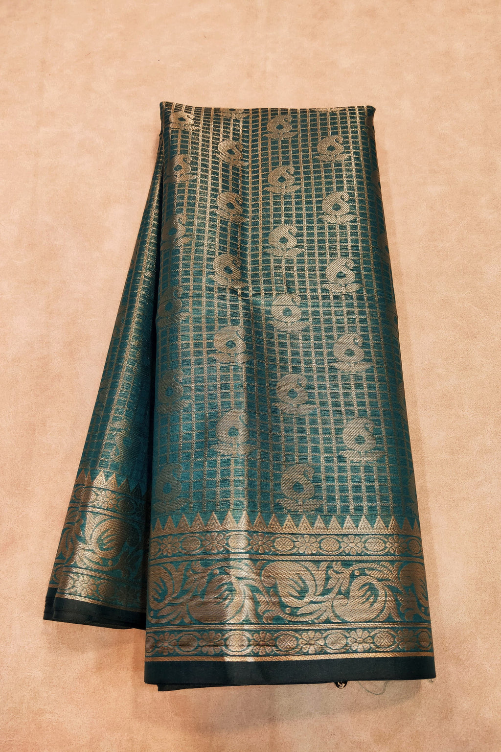 Teal and gold patterned fabric on a beige background