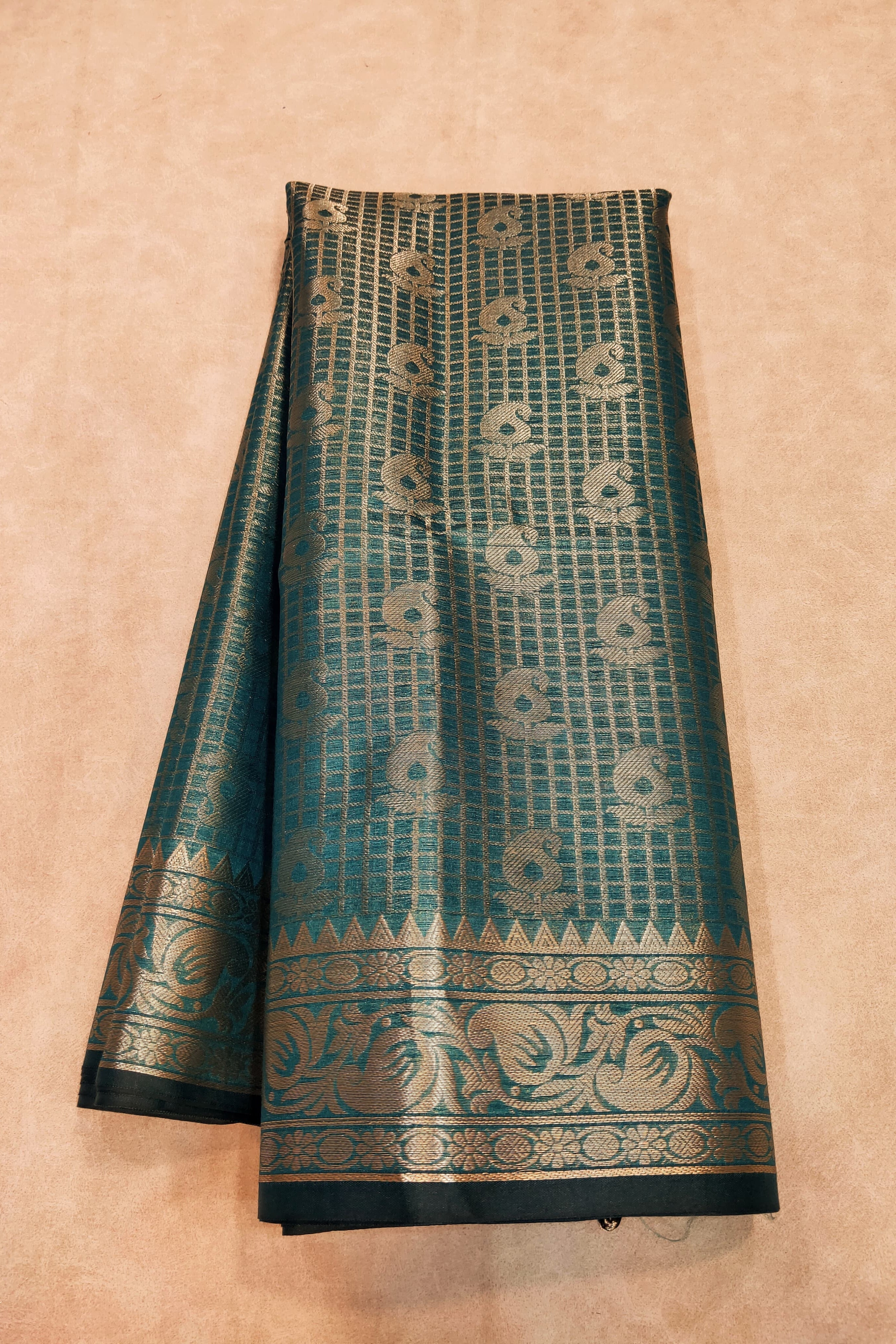 Teal and gold patterned fabric on a beige background