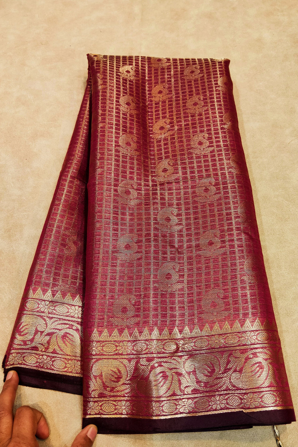 Maroon saree with gold patterns on a beige surface