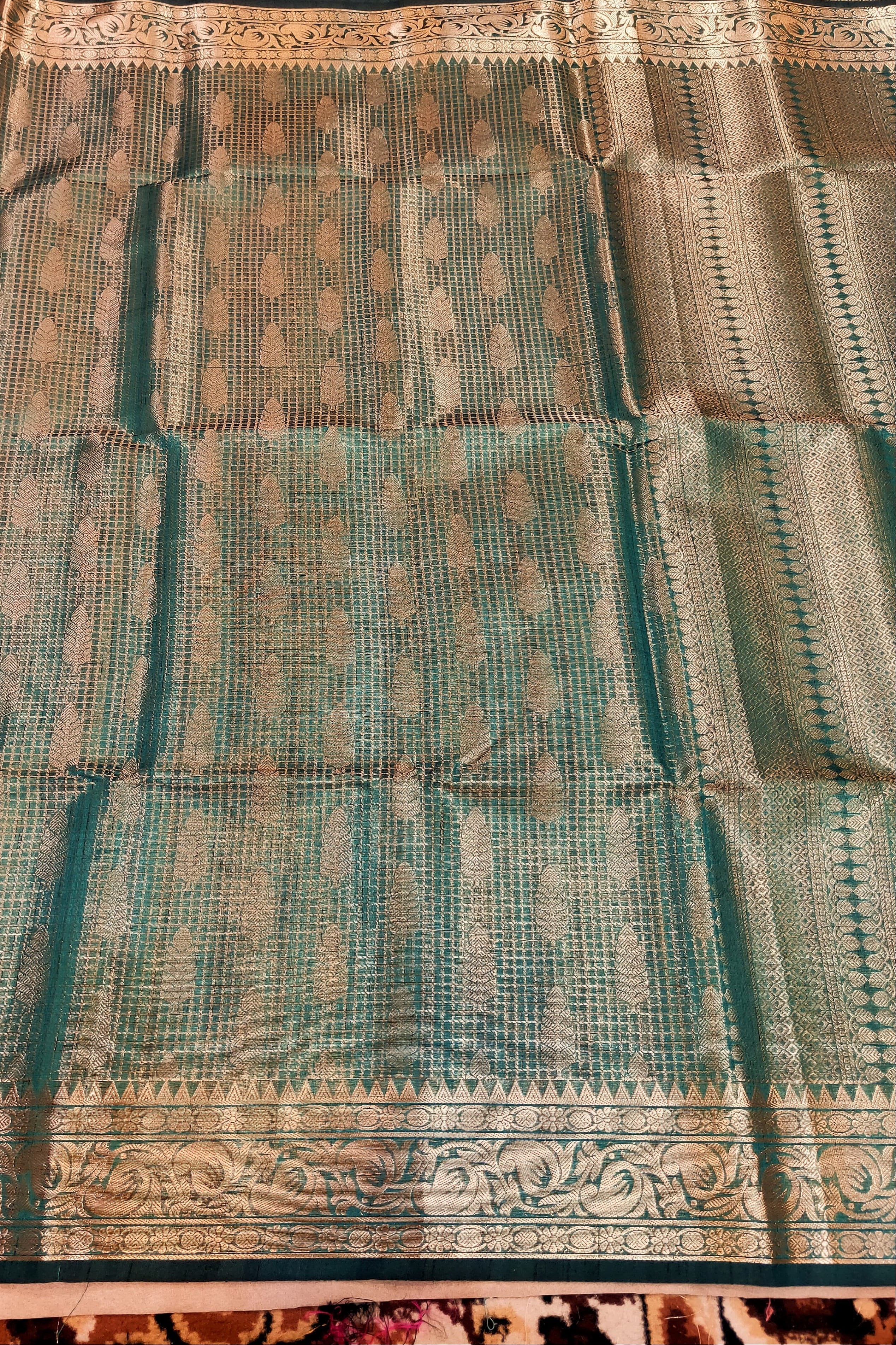 Teal and gold patterned fabric on a wooden surface