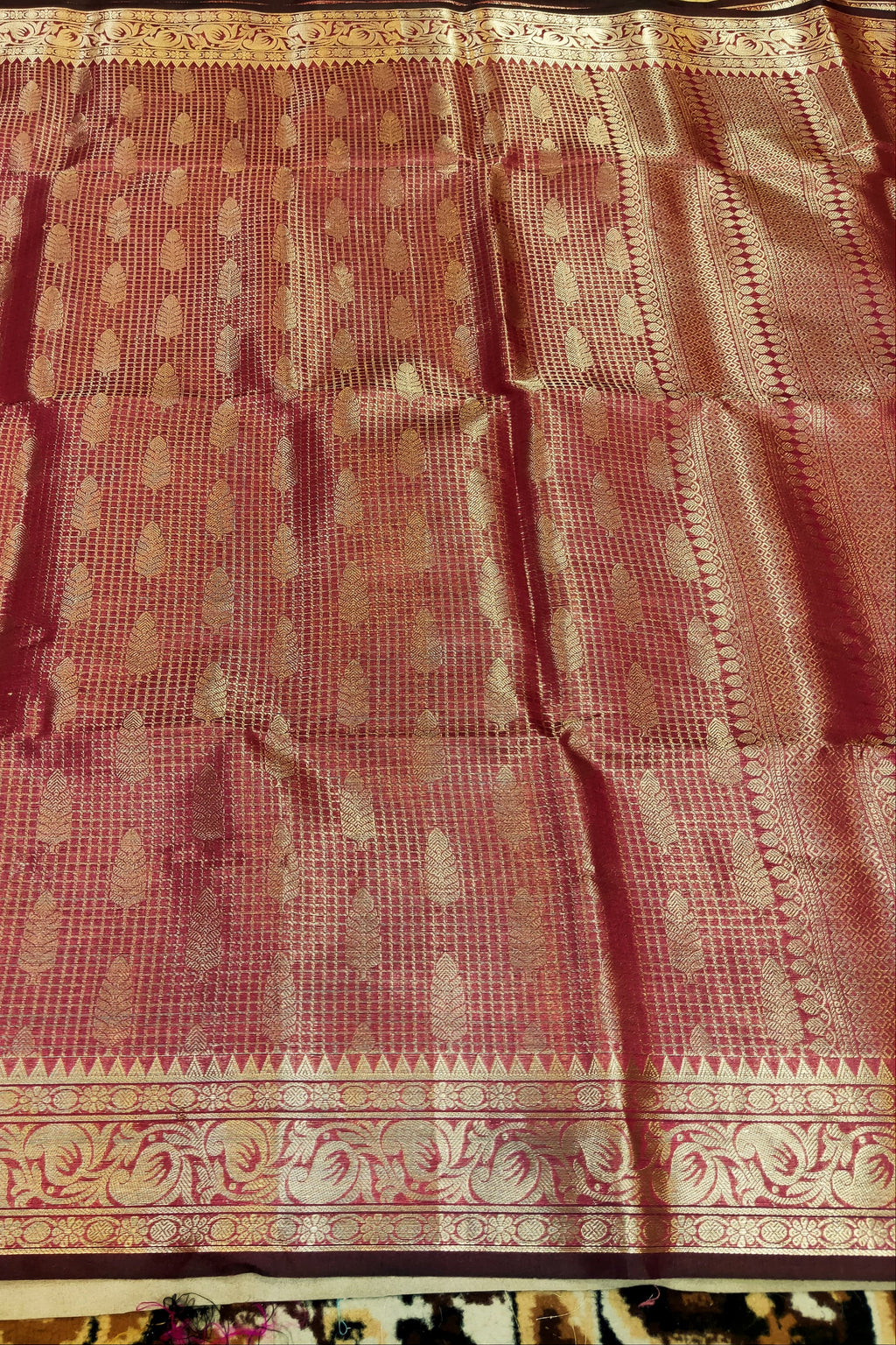 Red saree with gold patterns on a plain background