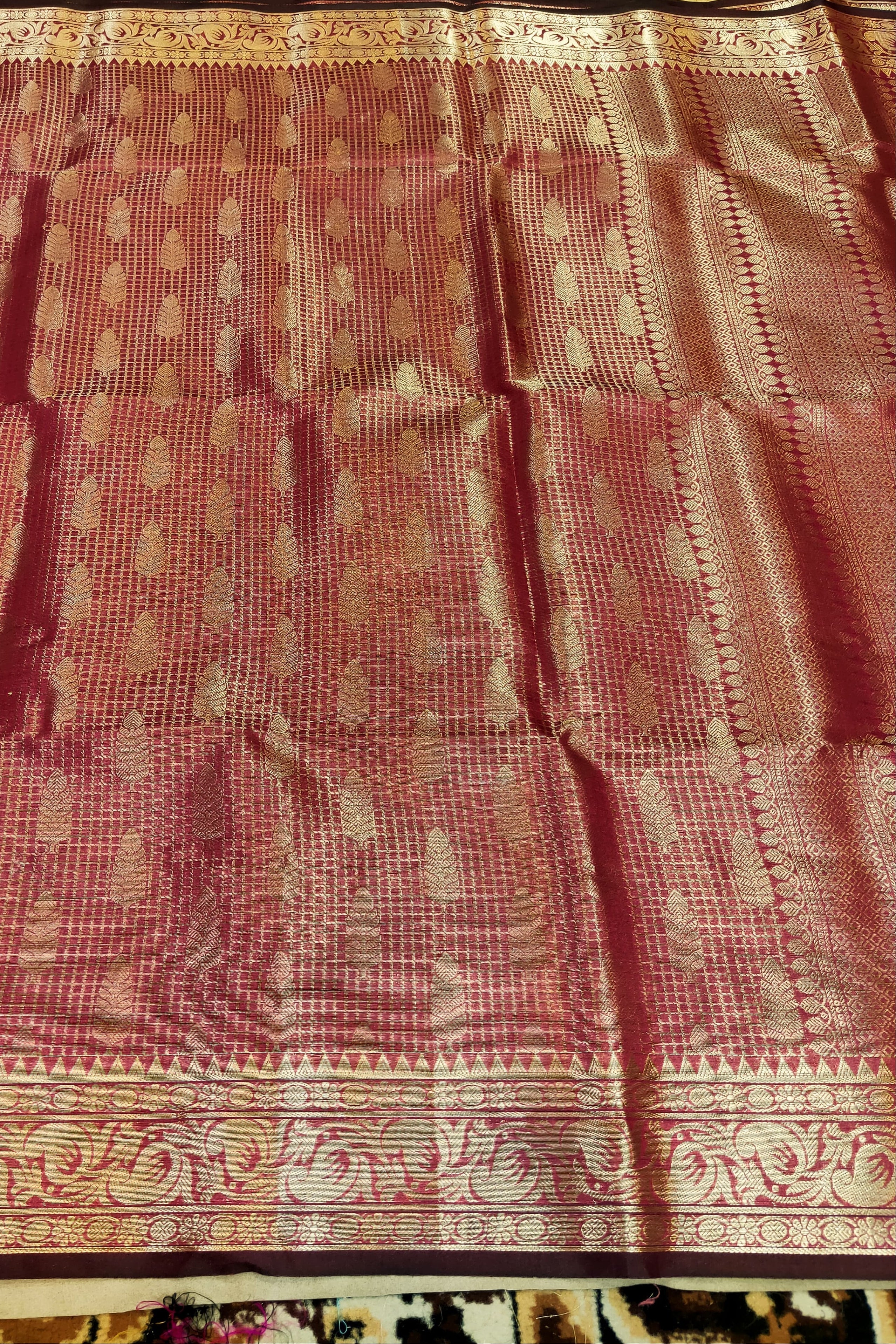 Red saree with gold patterns on a plain background