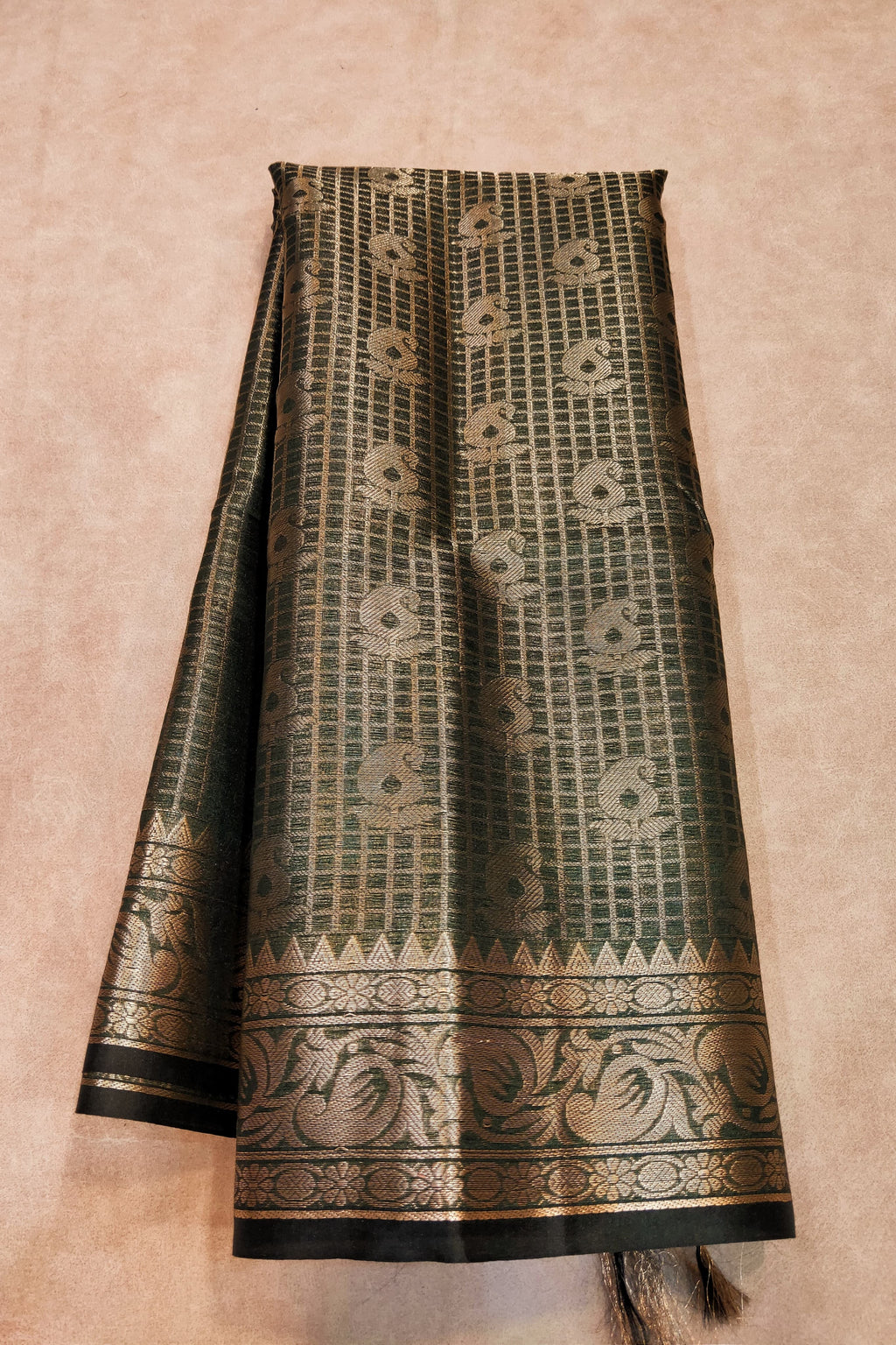 Traditional patterned fabric with black and gold design on a beige background