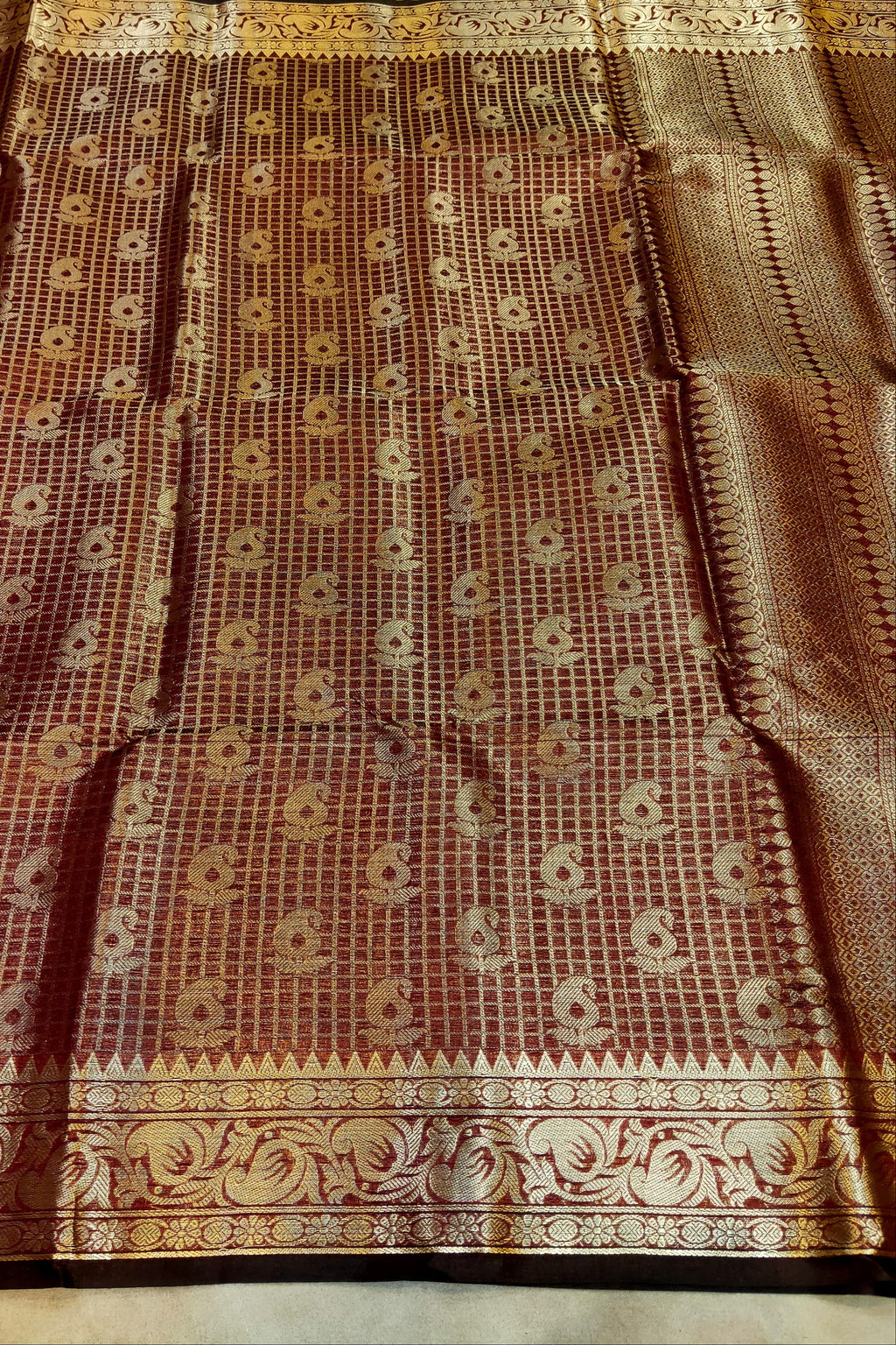 Brown saree with intricate patterns on a plain background