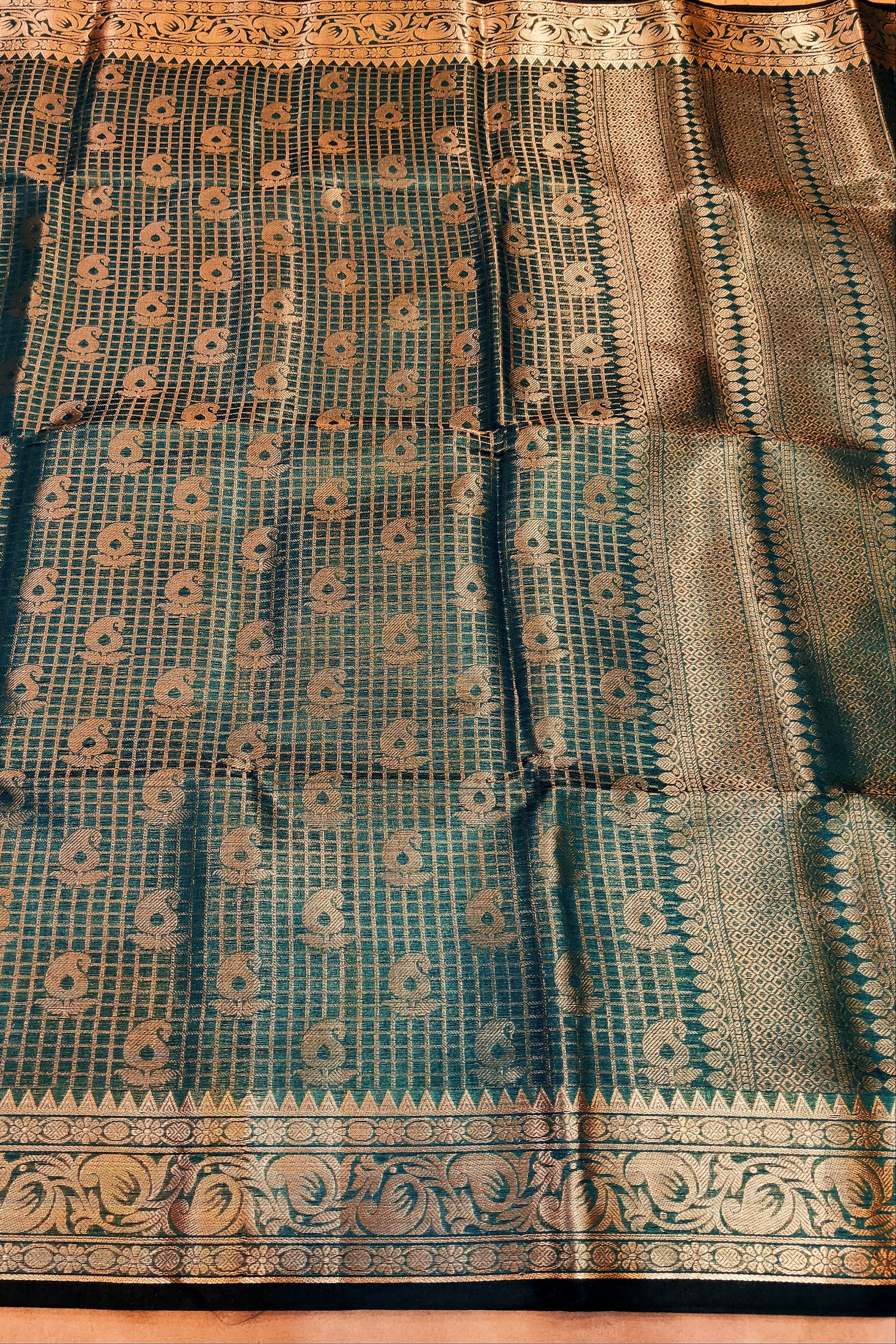 Green saree with intricate patterns on a wooden surface