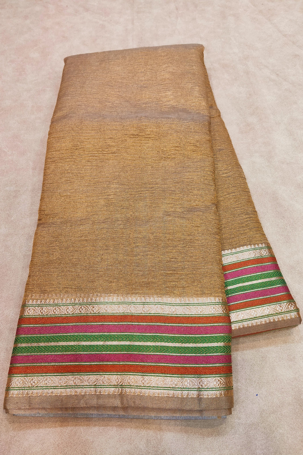 Brown fabric with colorful striped border on a beige background