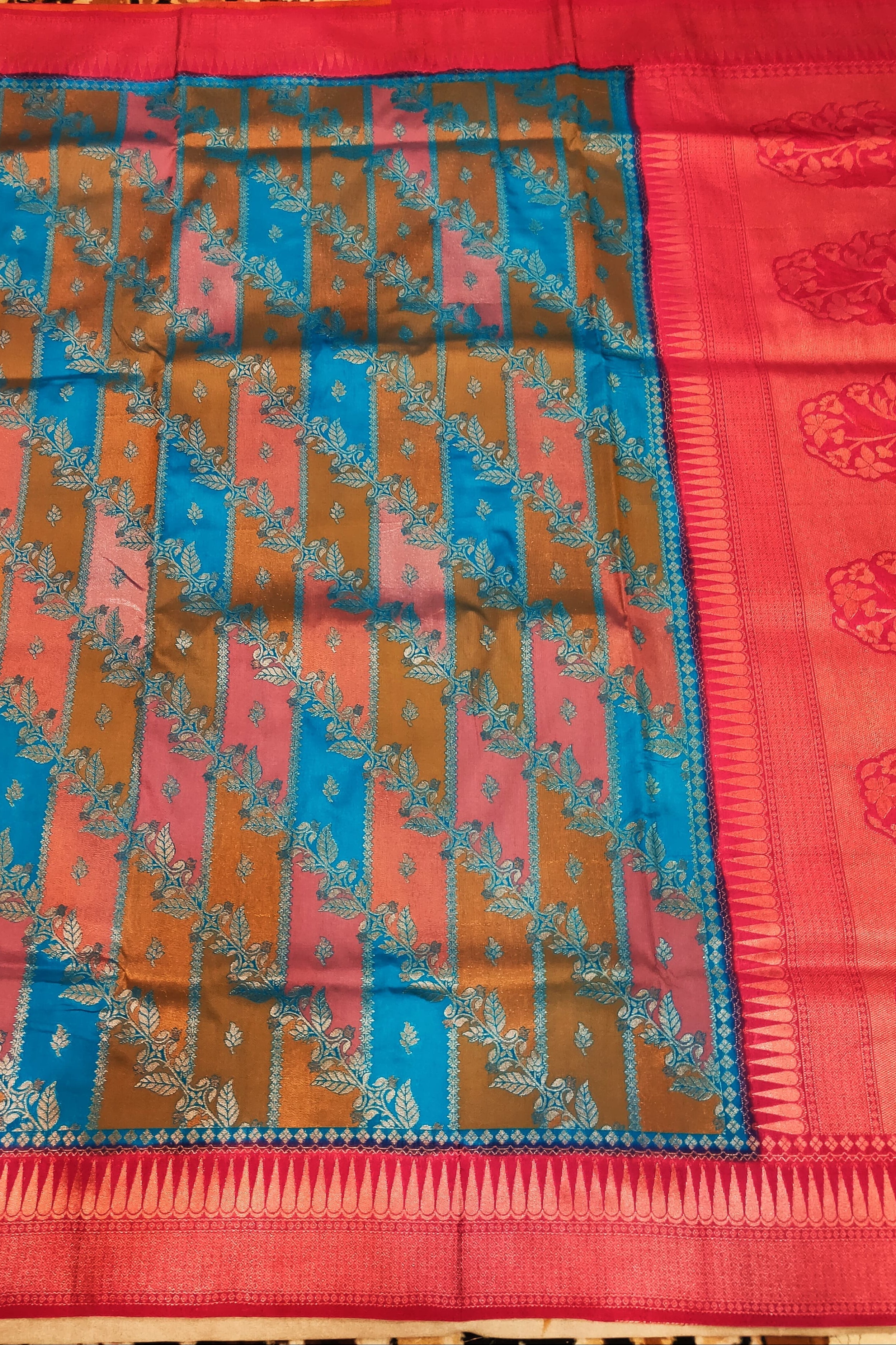 Colorful patterned fabric with a red border on a wooden surface
