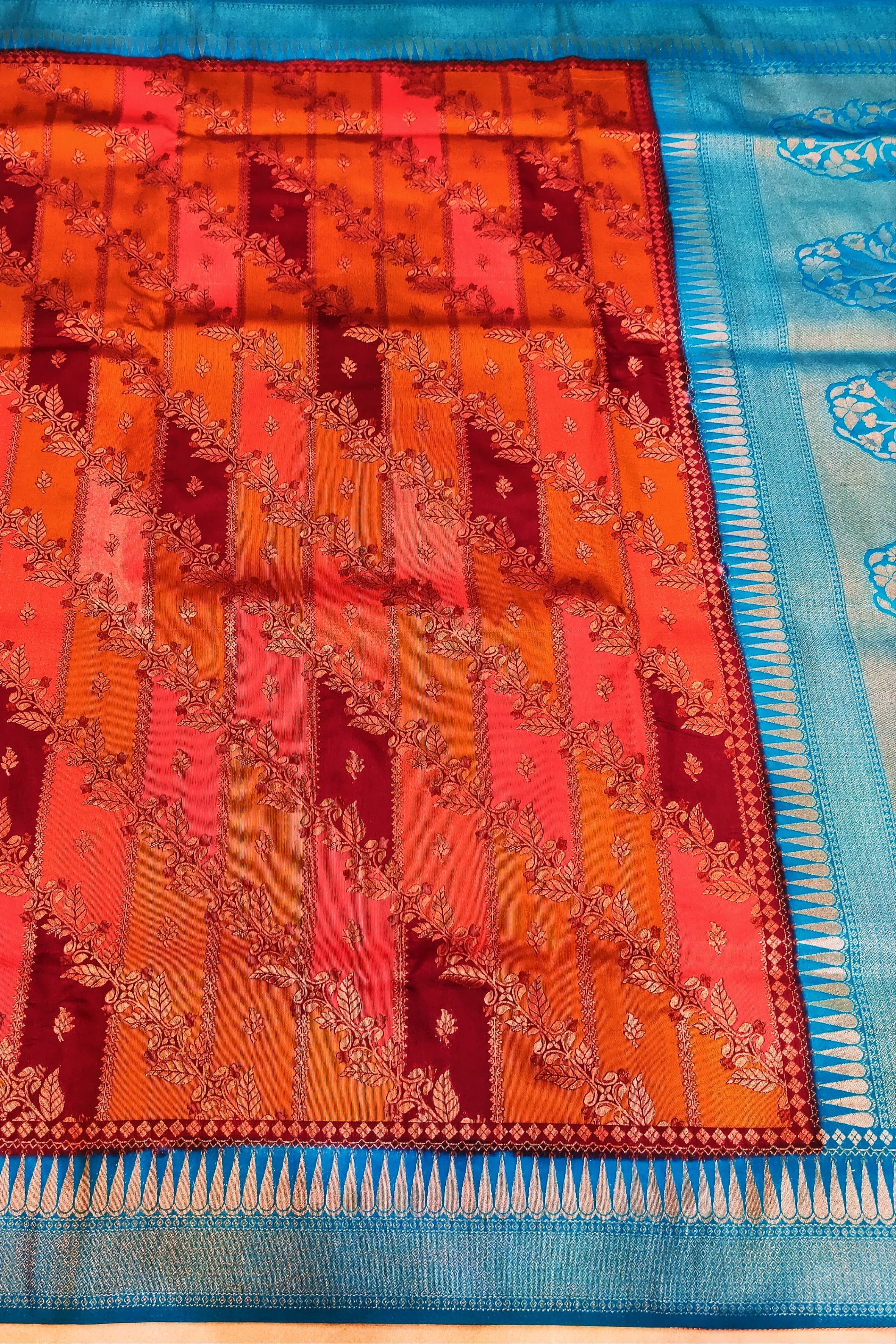 Colorful saree with a patterned border on a wooden surface