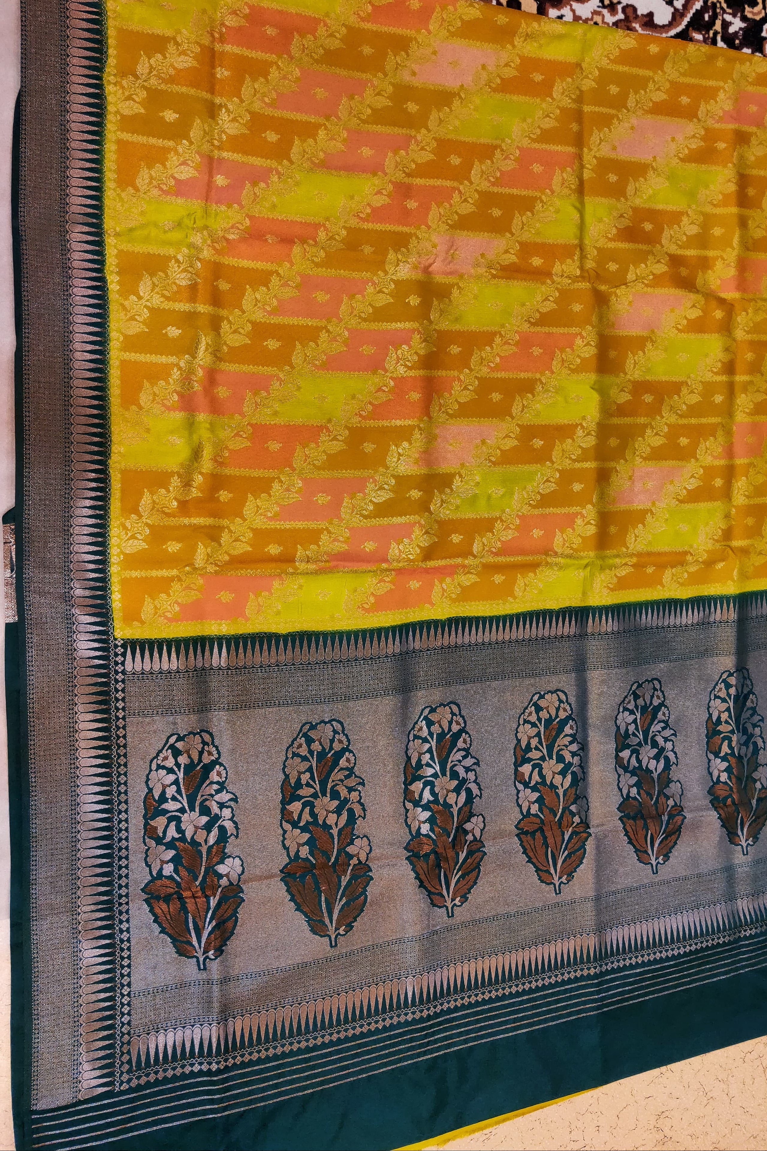 Yellow saree with a black border featuring floral patterns on a textured surface.