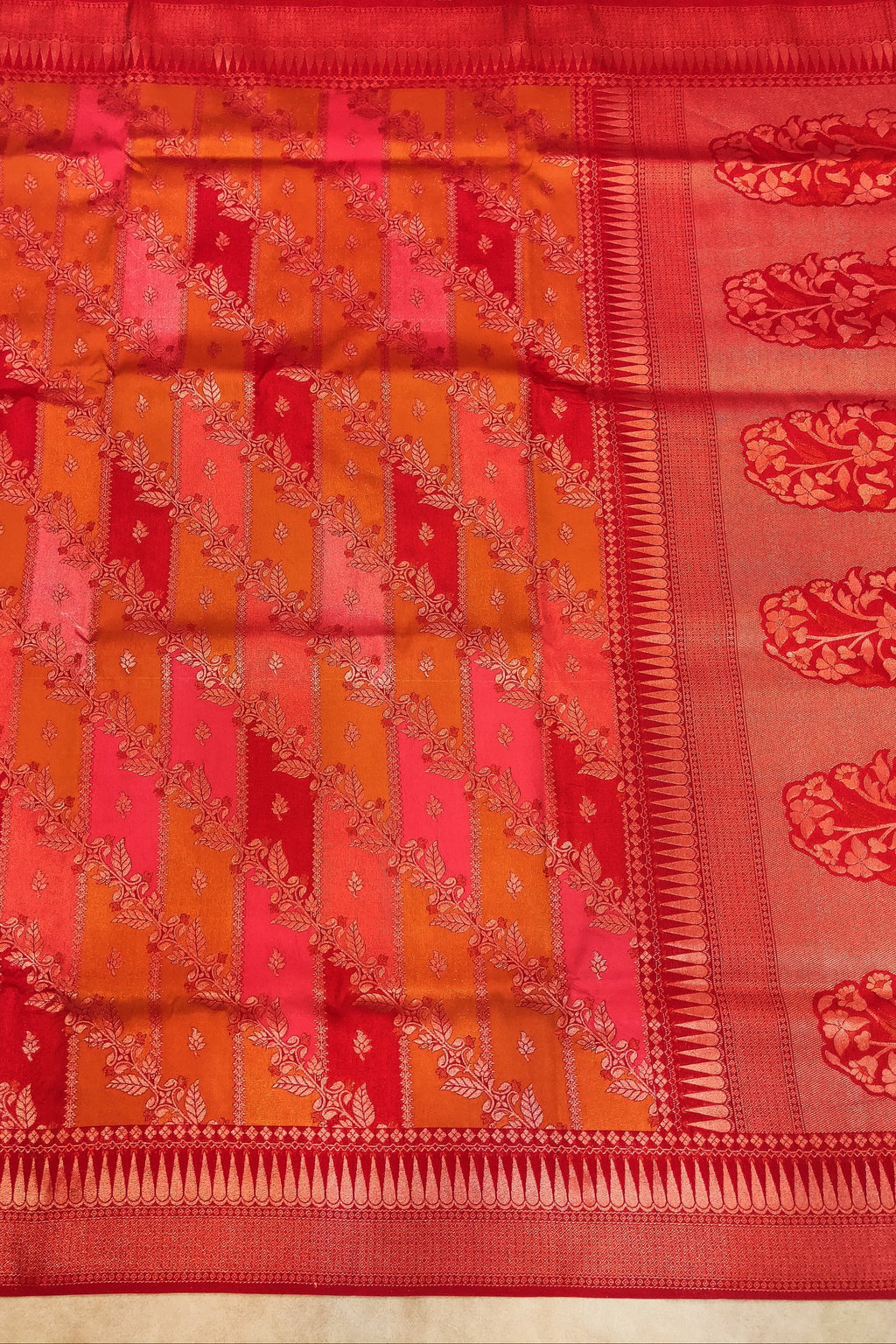 Traditional saree with a red and orange pattern on a plain background