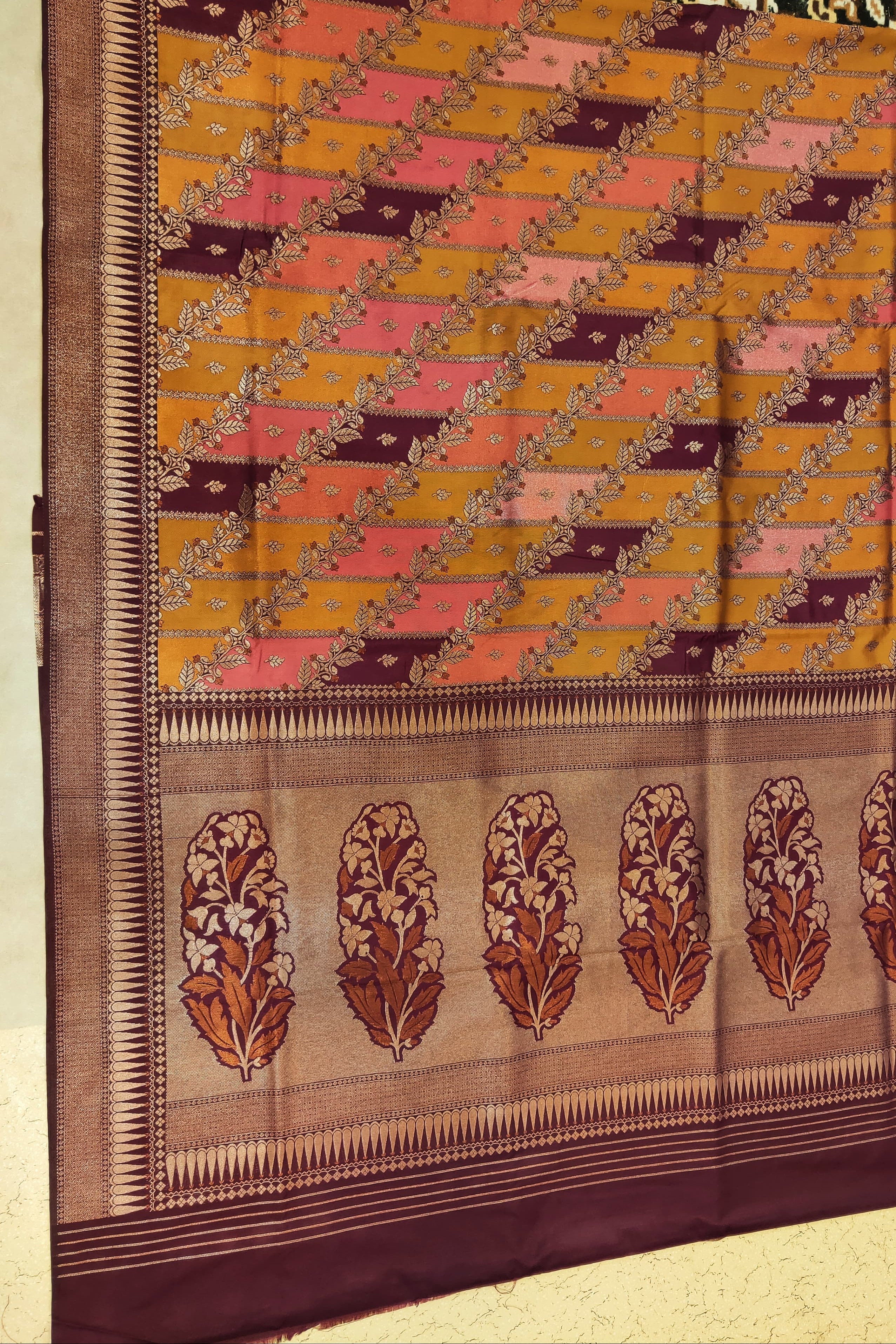 Traditional woven fabric with a diamond pattern and floral border on a beige background
