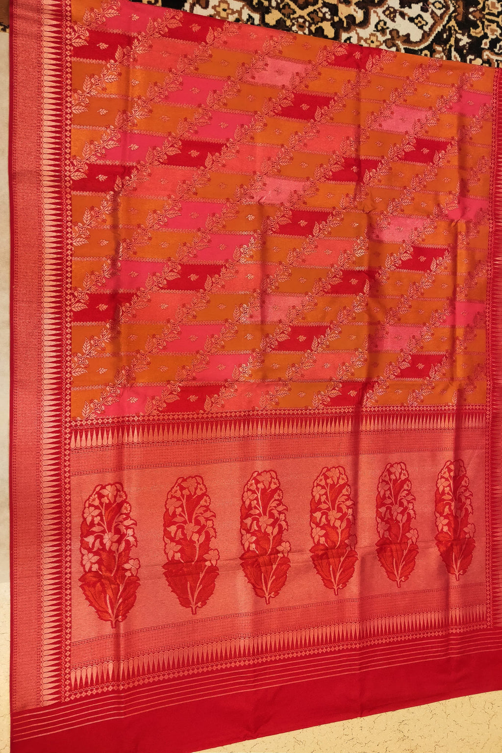 Red and orange saree with a geometric pattern on a plain background