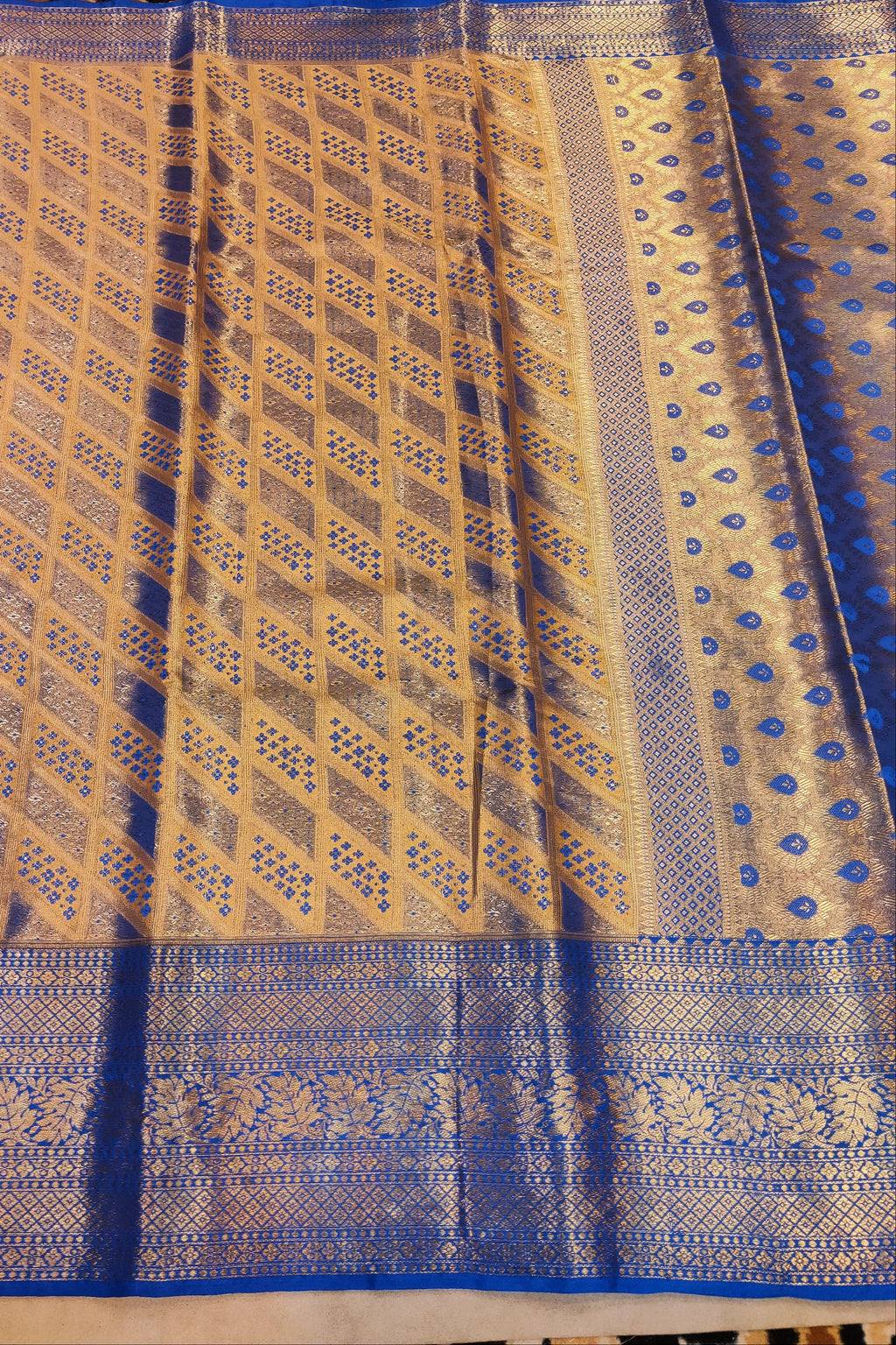 Blue and gold patterned fabric on a textured surface