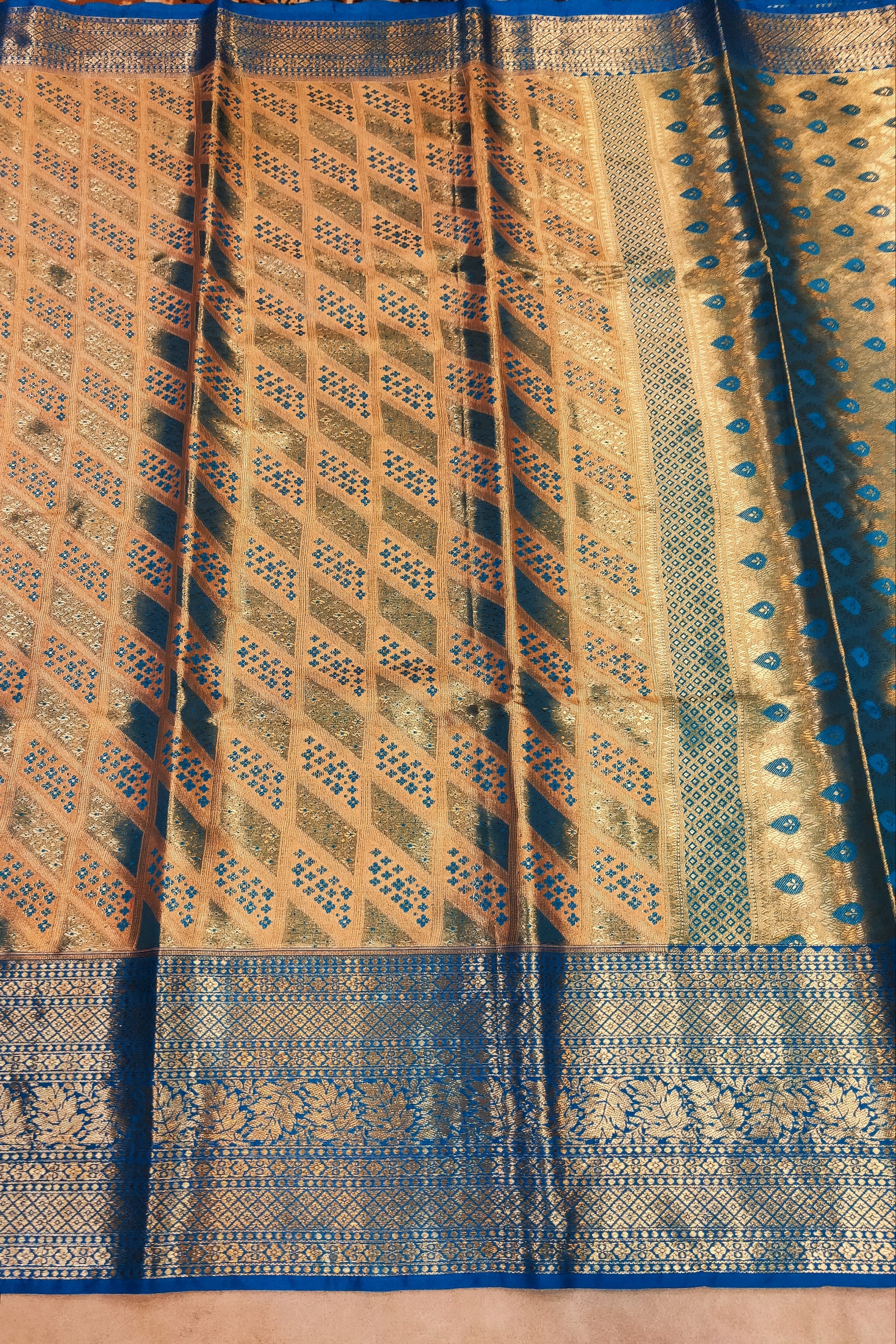 Traditional patterned fabric with blue and gold colors on a textured surface.