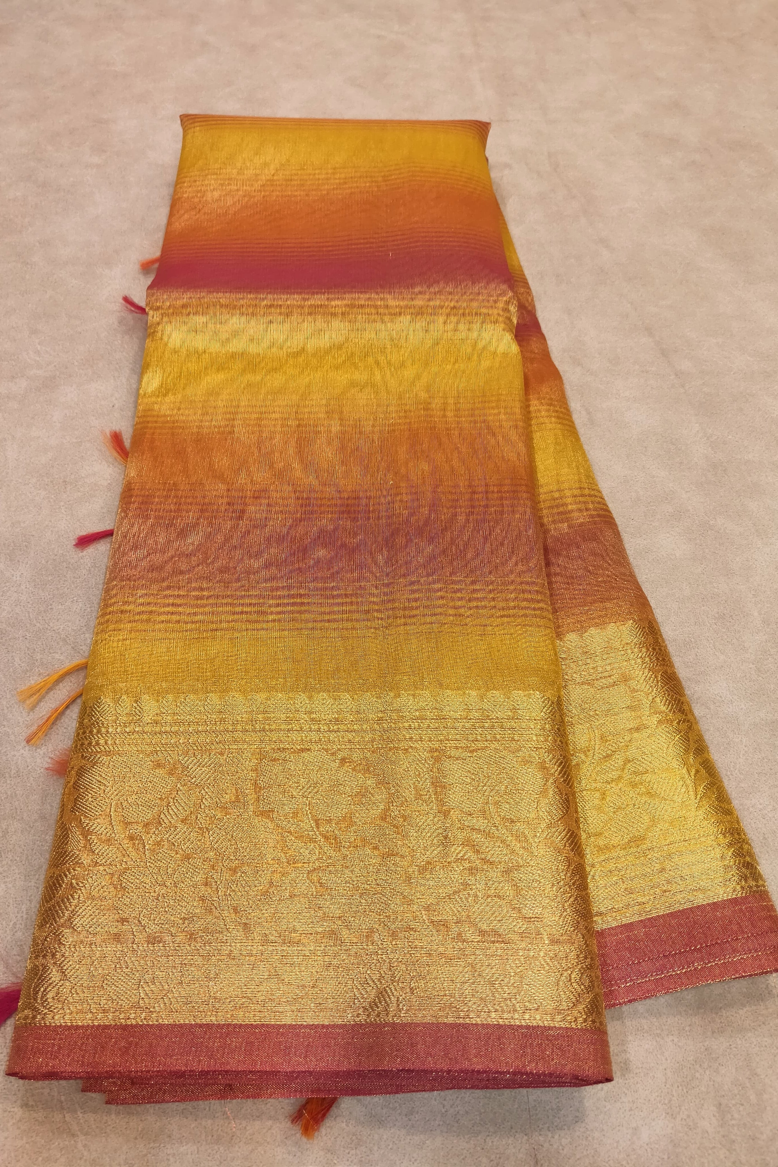 Colorful woven fabric with a gradient of orange, red, and gold on a beige background