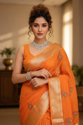 Woman in an orange saree with floral patterns indoors