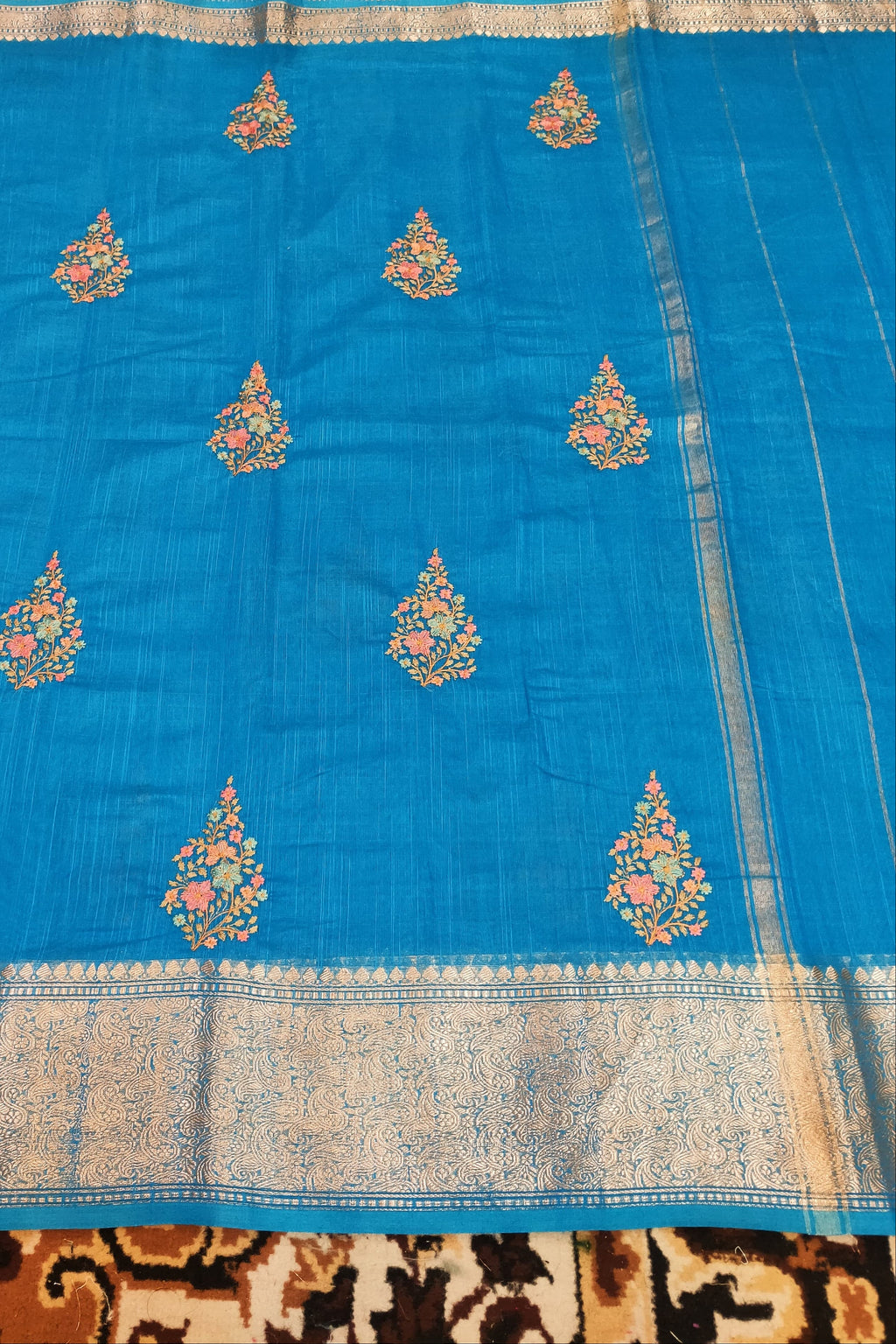 Blue saree with floral patterns on a patterned fabric background