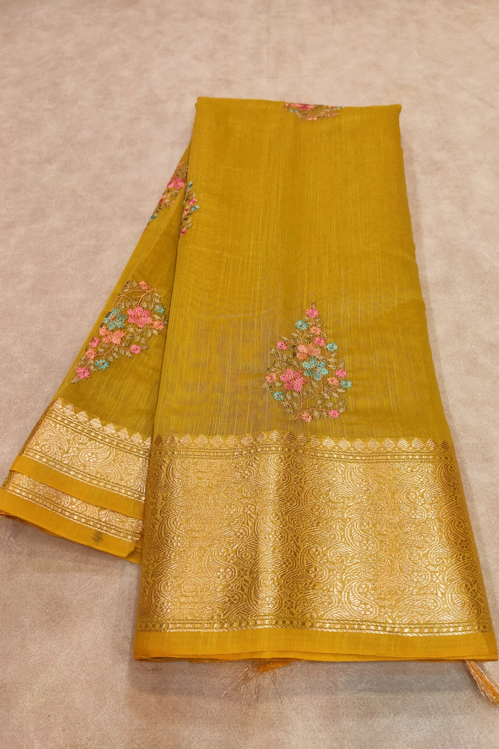 Yellow fabric with floral embroidery on a beige background