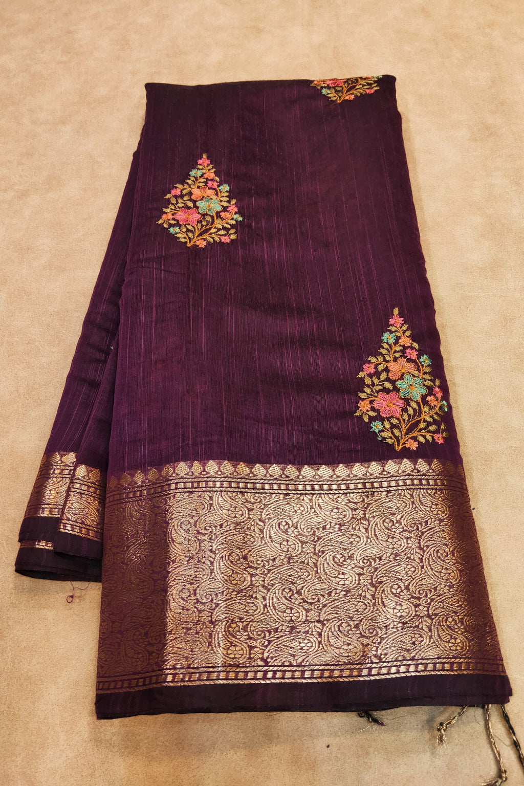 Purple fabric with floral embroidery on a beige background