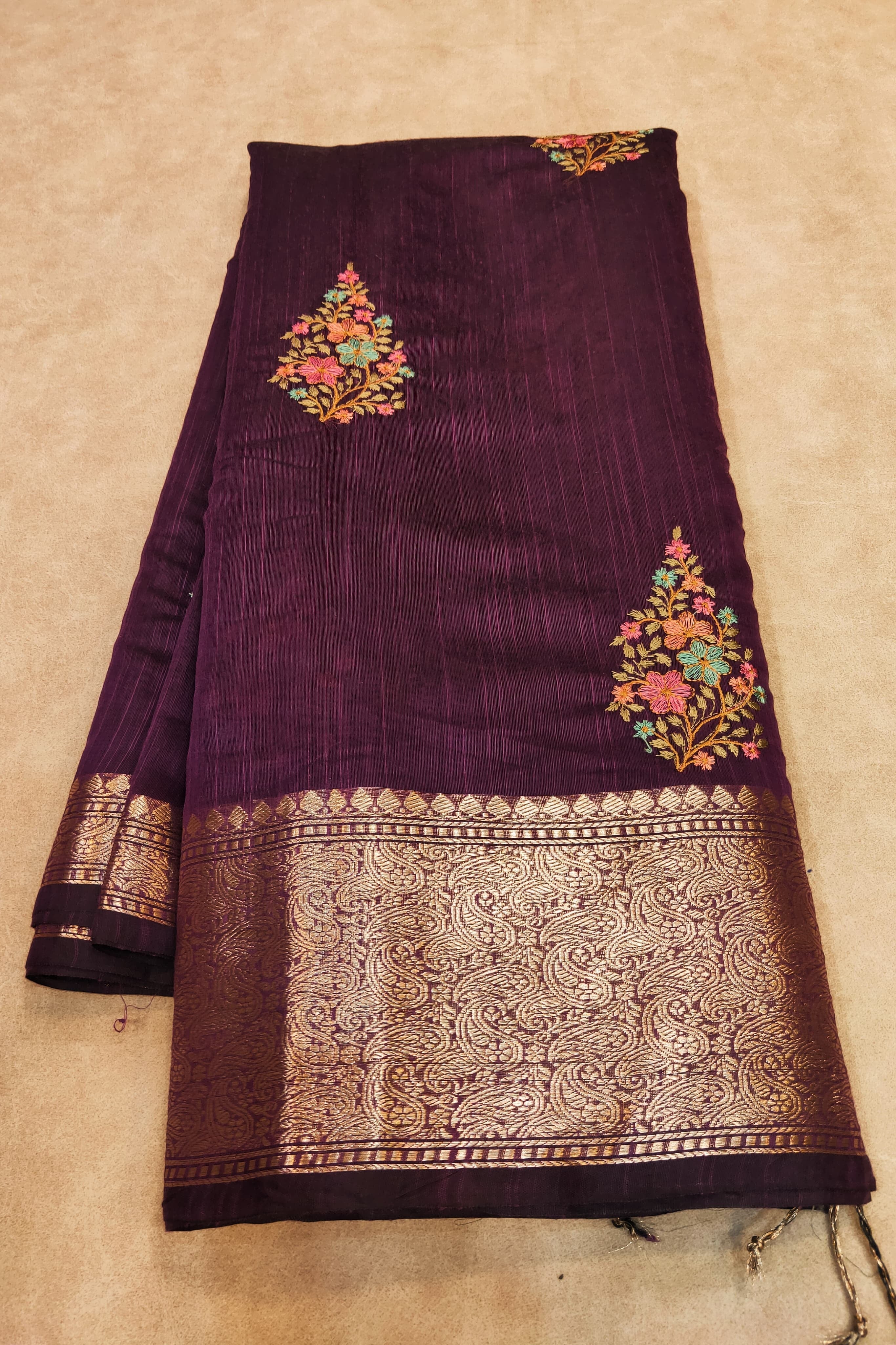 Purple fabric with floral embroidery on a beige background