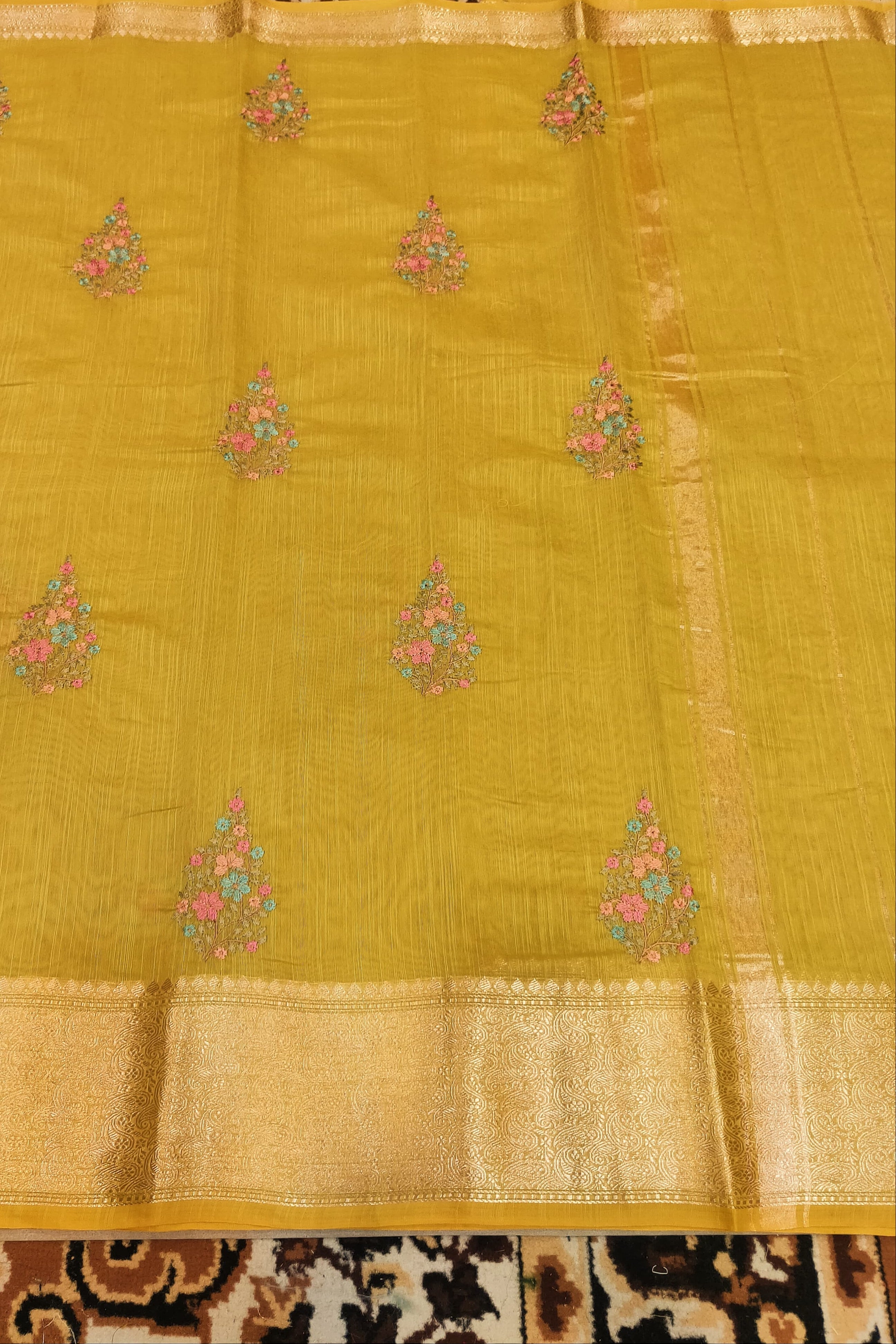 Yellow saree with floral patterns on a patterned fabric background