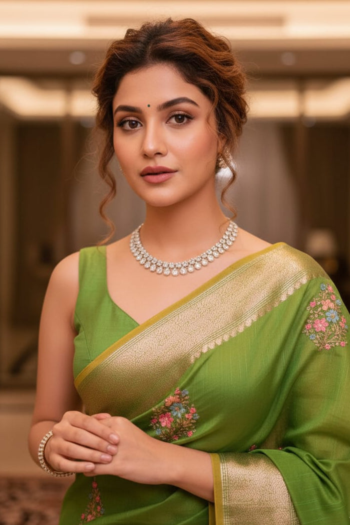 Woman in a green saree with gold border indoors