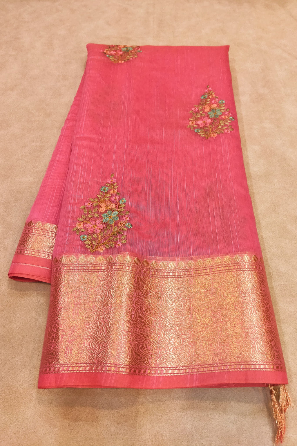 Pink saree with gold embroidery on a beige background