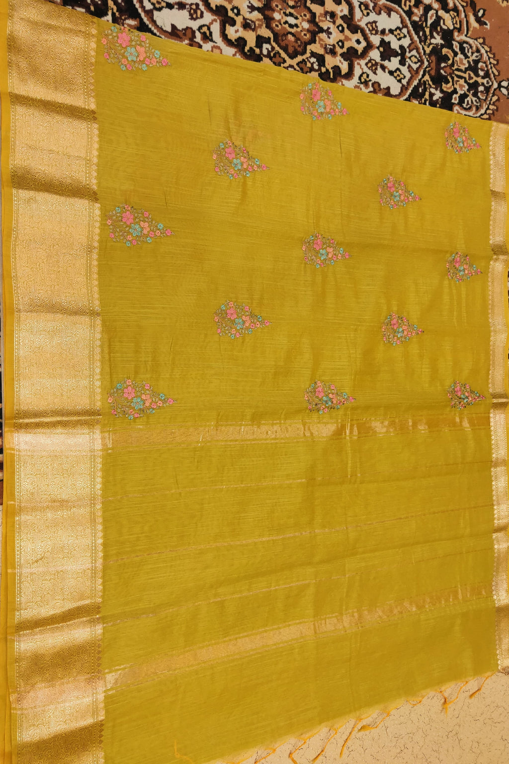 Yellow saree with floral patterns on a patterned fabric background