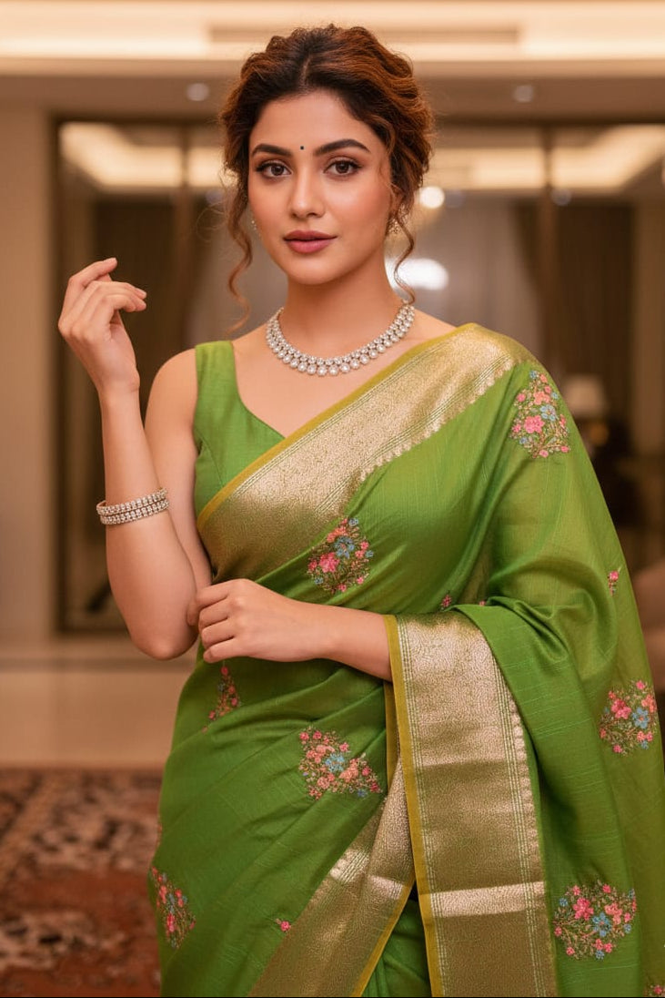 Woman wearing a green saree with floral patterns indoors.
