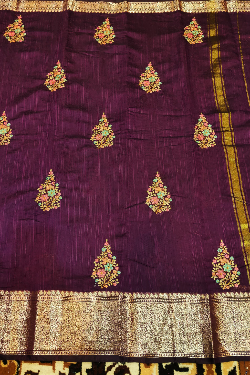 Purple saree with gold and multicolor embroidery on a patterned background