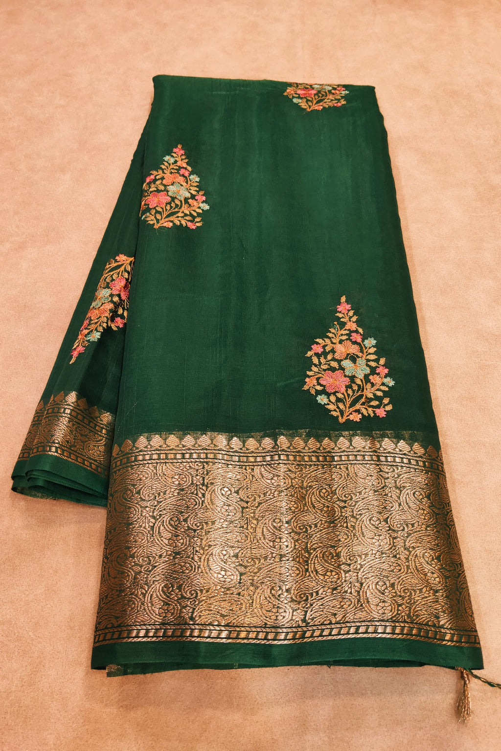 Green saree with floral embroidery on a beige background