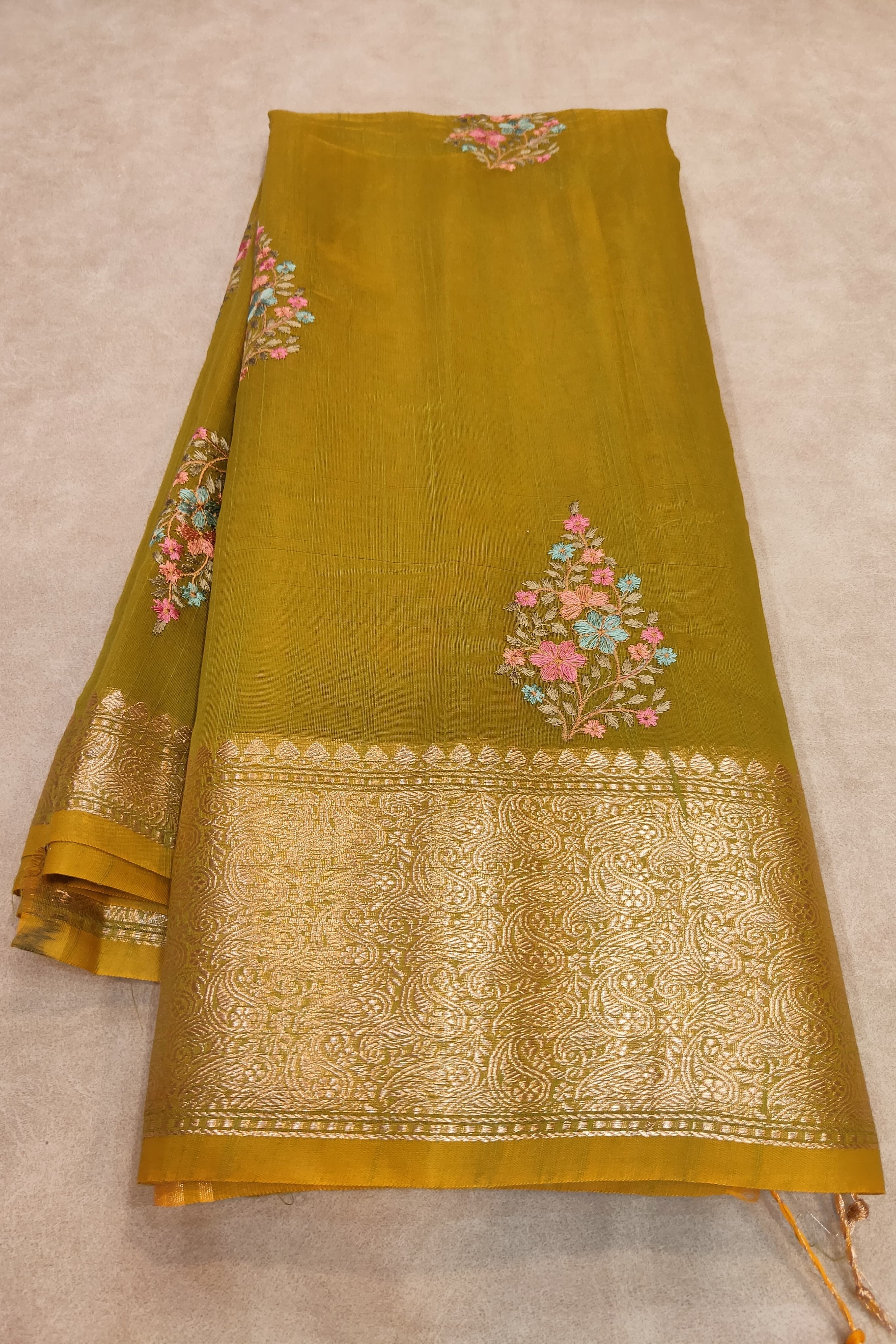 Mustard yellow fabric with floral embroidery on a beige background