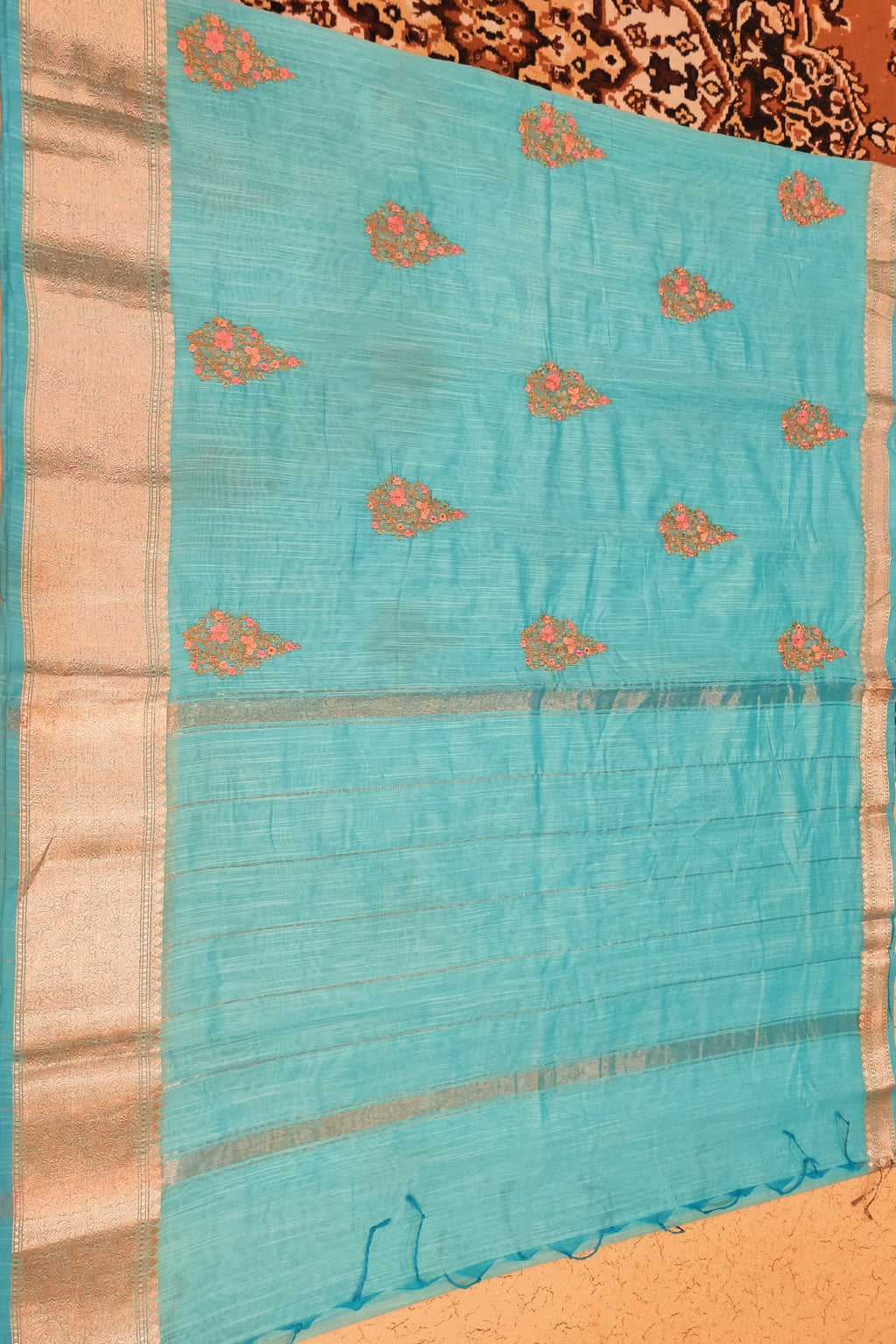 Turquoise saree with gold patterns on a patterned background
