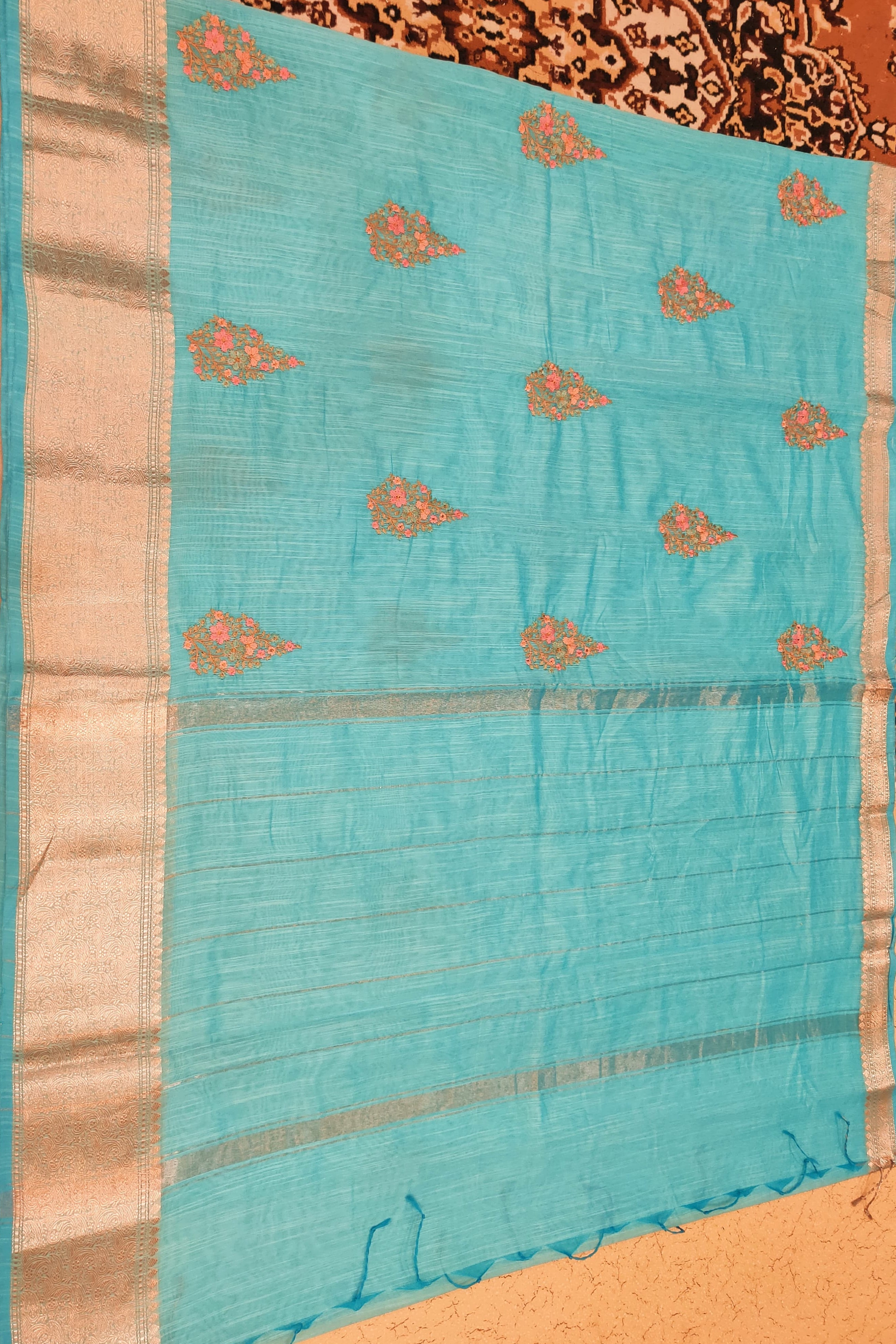 Turquoise saree with gold patterns on a patterned background
